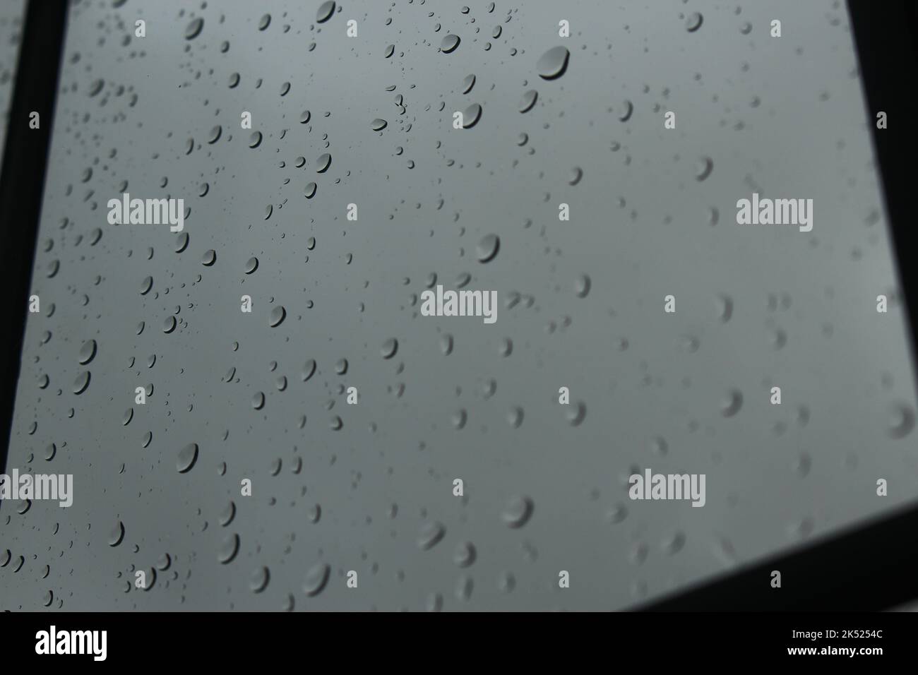 An einem bewölkten, nebligen Tag fällt Regen auf das klare Glasfenster. Konzept für Low Mood, Depression, aus der Art, grau, traurig, Regnerische Tage, in Innenräumen stecken geblieben Stockfoto