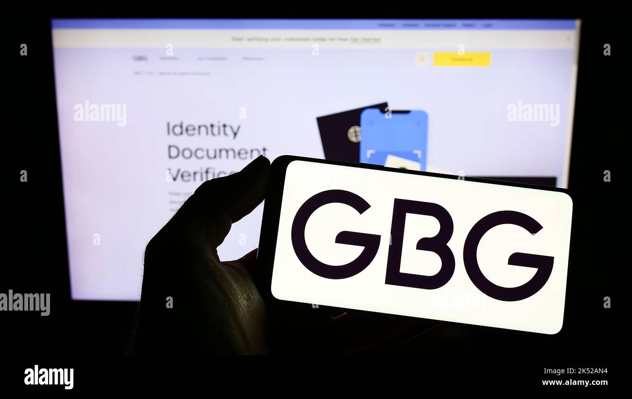 Person, die ein Smartphone mit dem Logo der Firma GB Group plc (GBG) auf dem Bildschirm vor der Website hält. Konzentrieren Sie sich auf die Telefonanzeige. Stockfoto