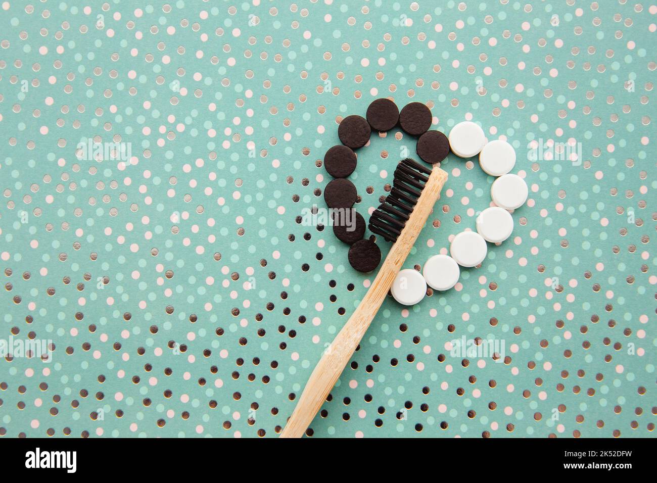 Oben Ansicht von schwarzen Aktivkohle- und weißen Fluorid-Zahnpasta-Tabletten mit Bambuszahnbürste. Zahnpflegekonzept. Minimal mintgrün gepunktet. Stockfoto