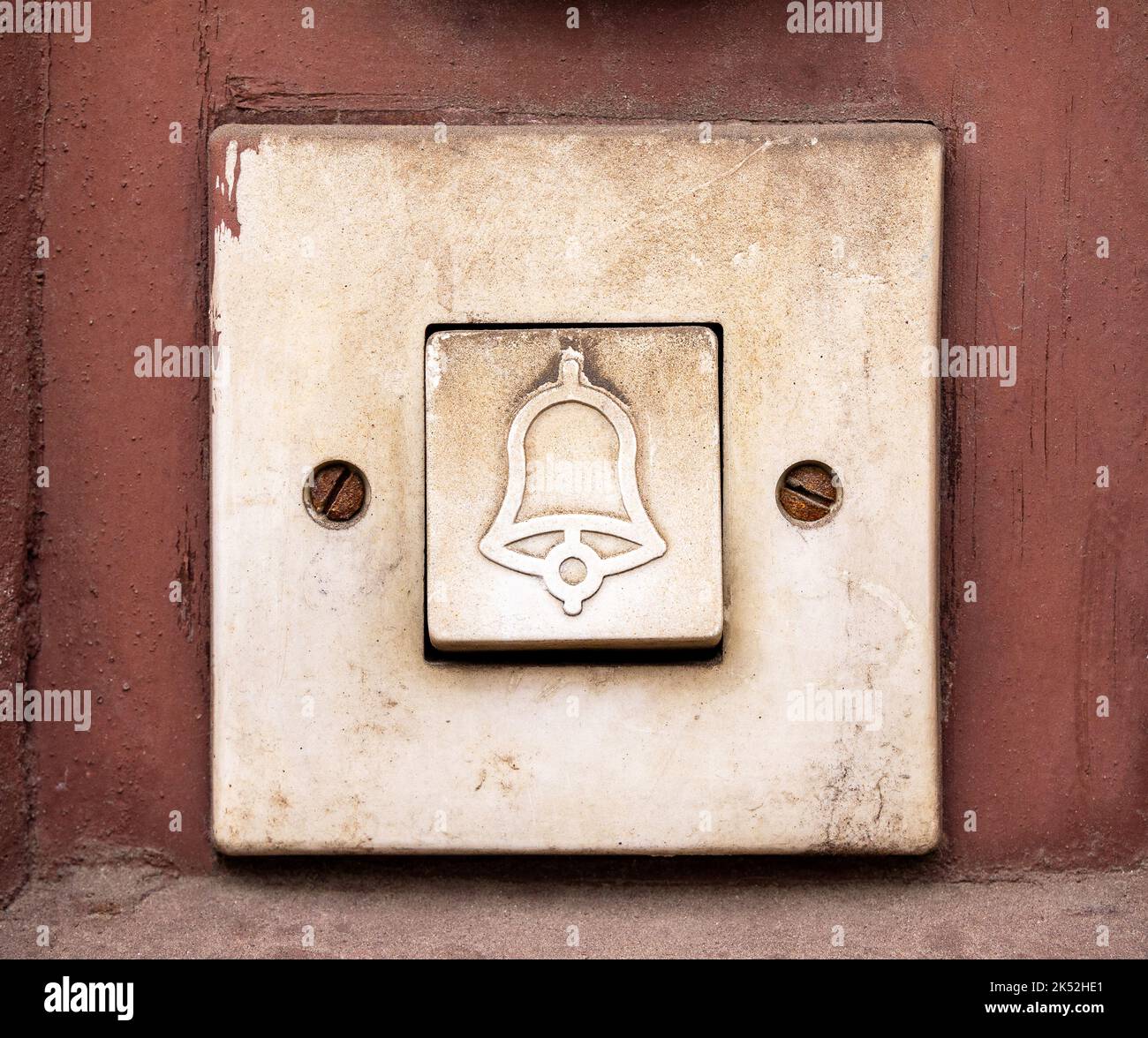 Einfache alte Türklingel, rechteckiger Türglockenschalter mit Glockensymbol darauf, Objekt-Makro, extreme Nahaufnahme, Vorderansicht, Frontalaufnahme, Niemand, keine Menschen. Stockfoto