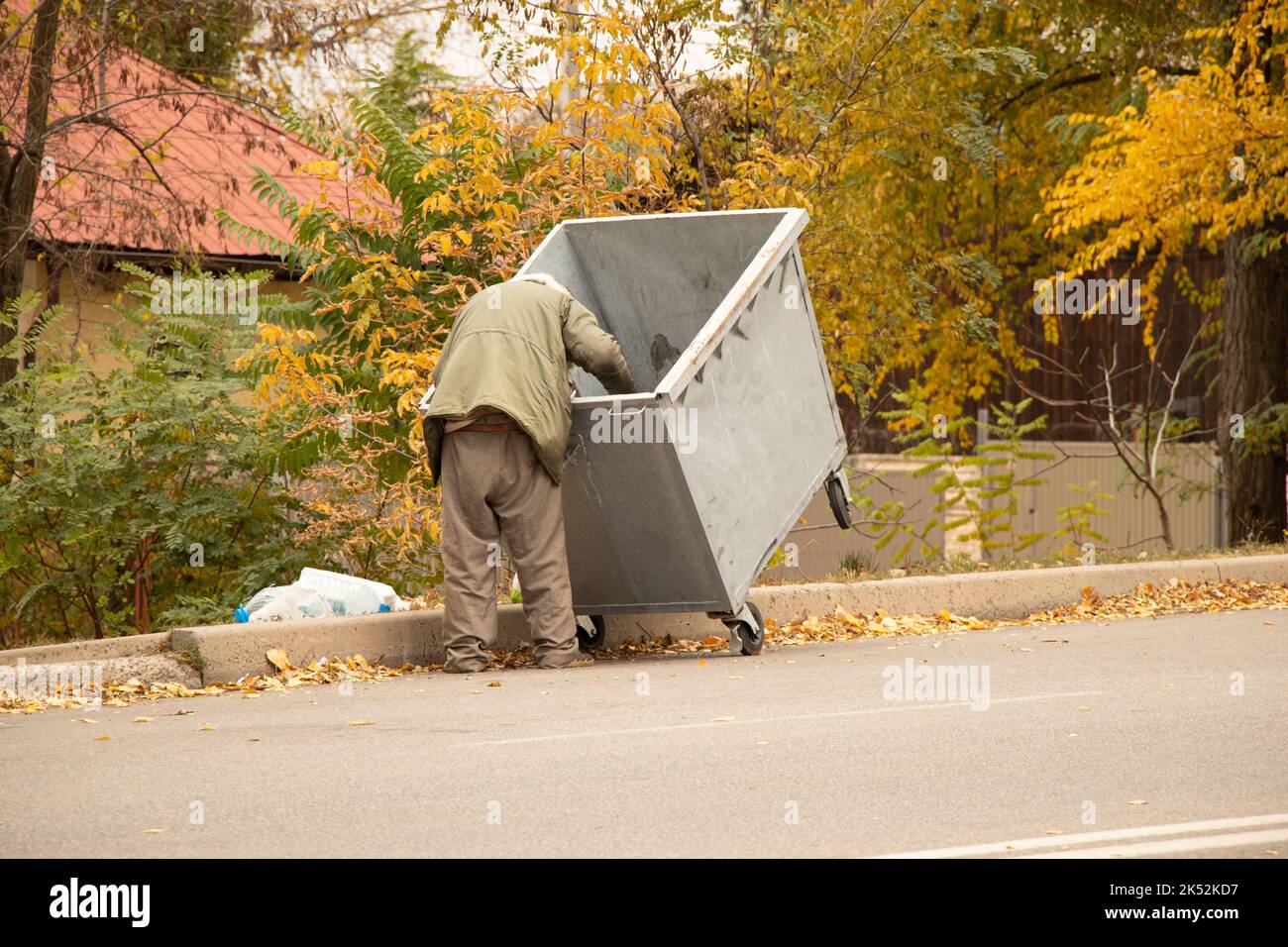 Schmutziger obdachloser Mann, der nach Essen im Mülleimer sucht, obdachloser Mann und Müllabfuhr, auf der Suche nach Nahrung, wandernder Mann Stockfoto