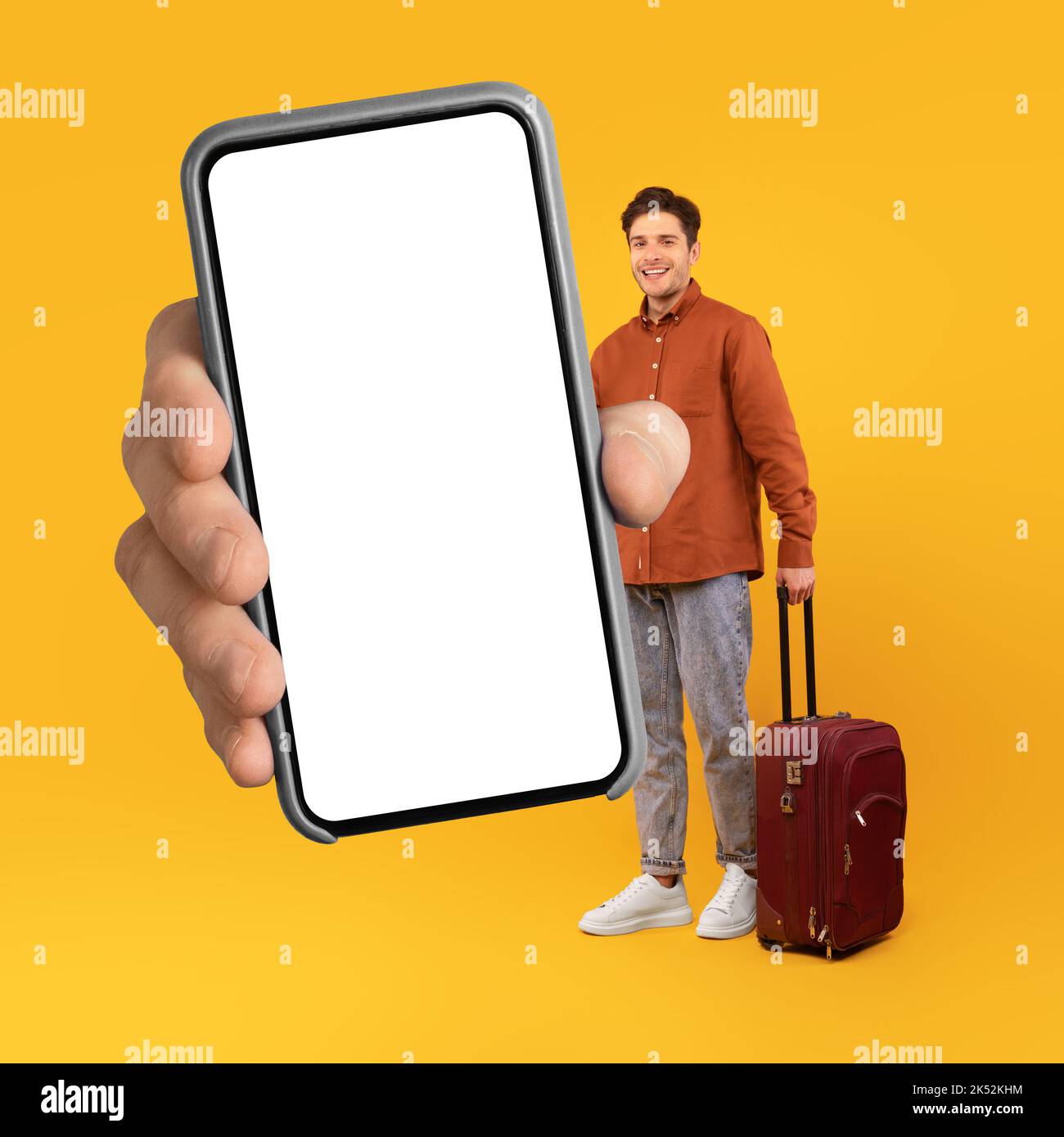 Männlicher Tourist Zeigt Großes Telefon Mit Leerem Bildschirm, Gelber Hintergrund Stockfoto