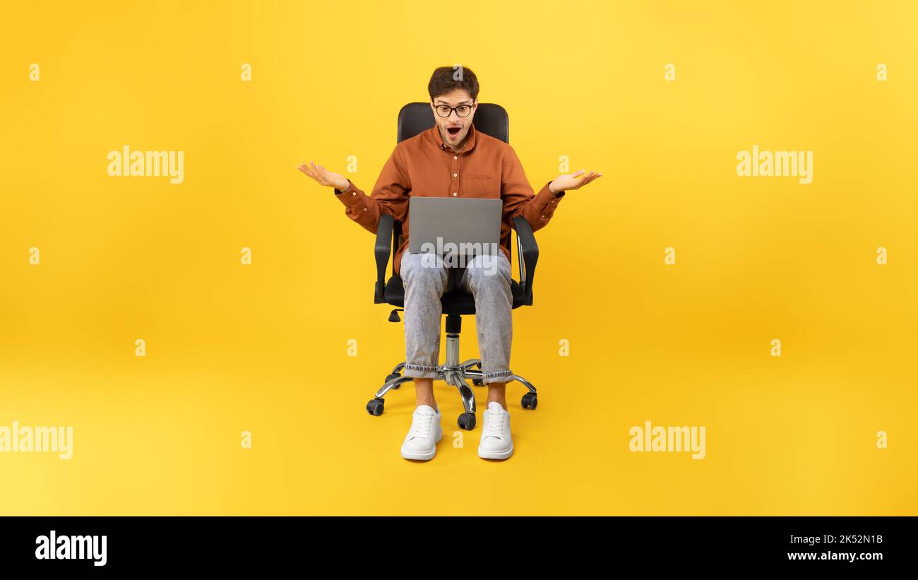 Schockiert Mann Mit Laptop Online-Arbeit Sitzen Auf Gelbem Hintergrund Stockfoto