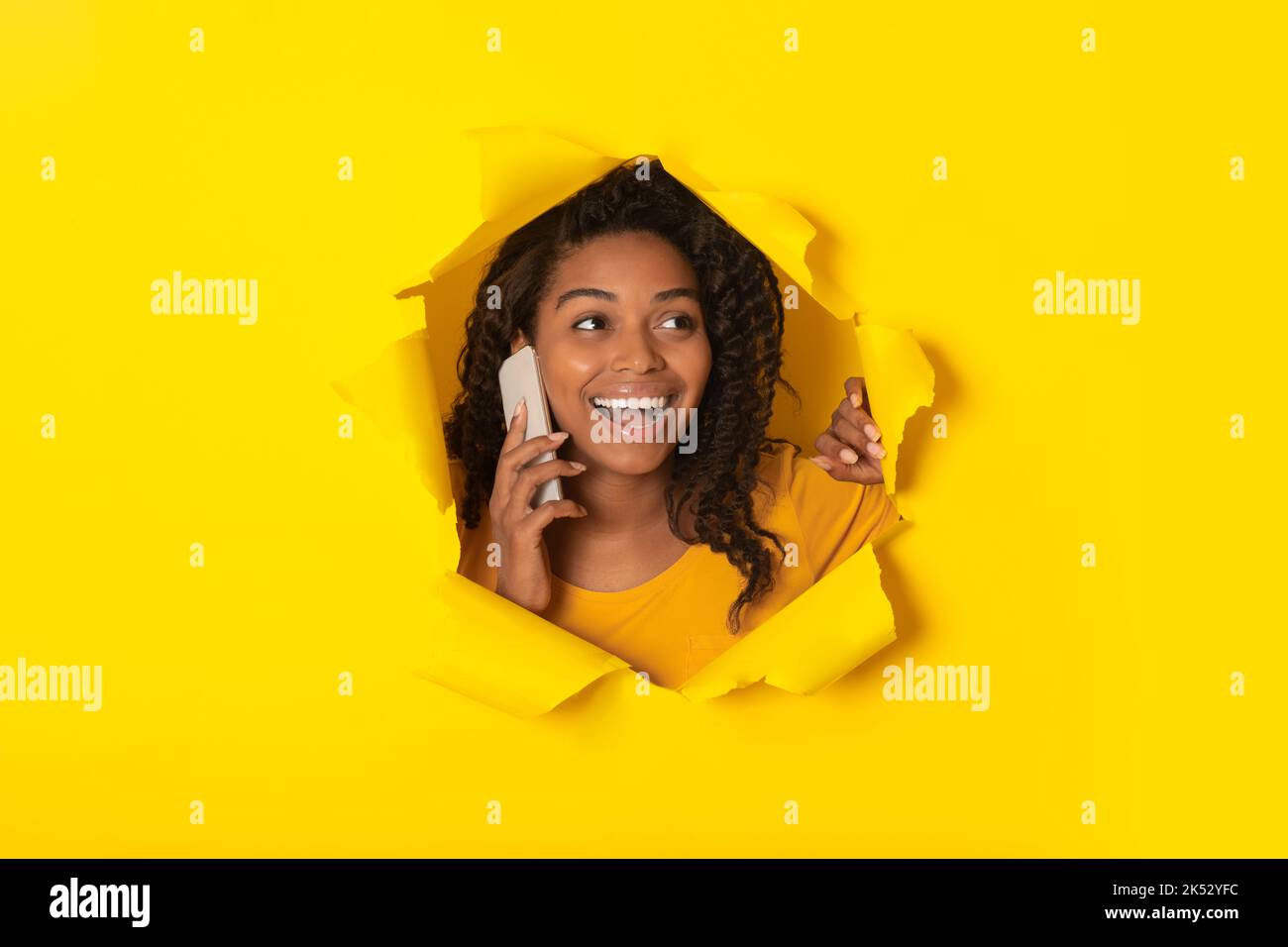 Schwarze Dame Im Gespräch Auf Handy Posiert In Loch In Papier Stockfoto