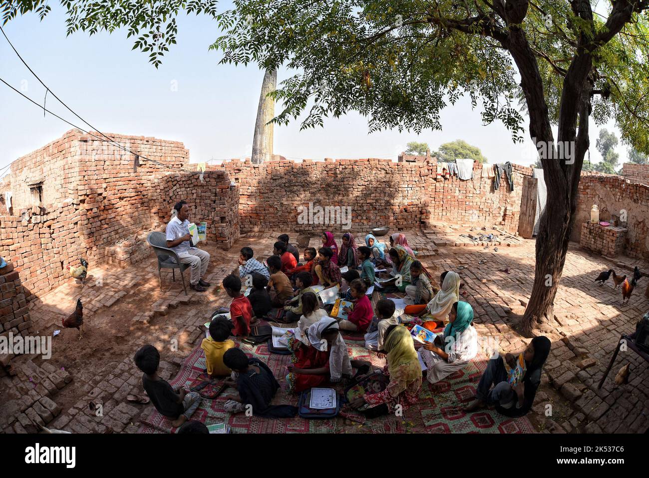 Lahore, Punjab, Pakistan. 5. Oktober 2022. Pakistanische Lehrer der United Social Welfare Society unterrichten ihre Klasse (Dissable Students Class) eine von der Regierung finanzierte Non-formal Basic Education School (NFBES) am Vorabend des Weltlehrertages an einem Ziegelofen in den Außenbezirken von Lahore. Anlässlich des Weltlehrertages, der seit 1994 jährlich am 5. Oktober stattfindet und an Lehrerorganisationen weltweit erinnert. Ziel ist es, die Unterstützung der Lehrer zu mobilisieren und sicherzustellen, dass die Bedürfnisse zukünftiger Generationen weiterhin von den Lehrern erfüllt werden. (Bild: © Rana Sajid Hussain/Pazifik Stockfoto