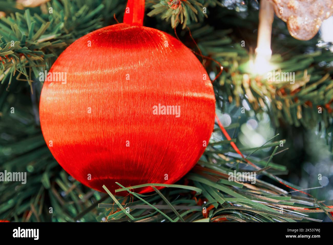 Leuchtend roter Weihnachtsbaum Spielzeugball auf dem Fichtenzweig im Innenraum. Hintergründe zum neuen Jahr Stockfoto