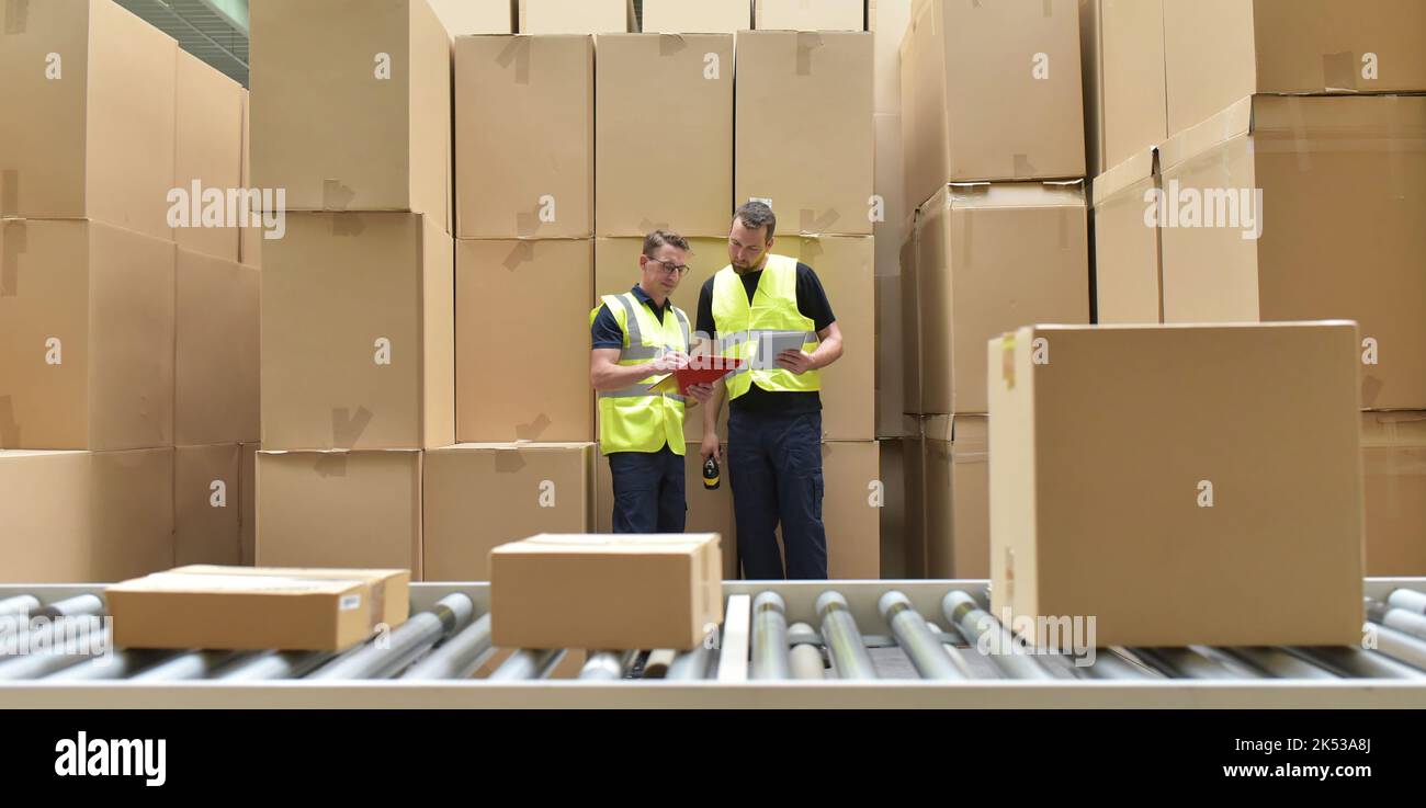 Arbeiter in einem Lager in der Logistik-Branche Verarbeitung von Paketen auf der Montagelinie - Transport und Verarbeitung von Aufträgen im Handel Stockfoto