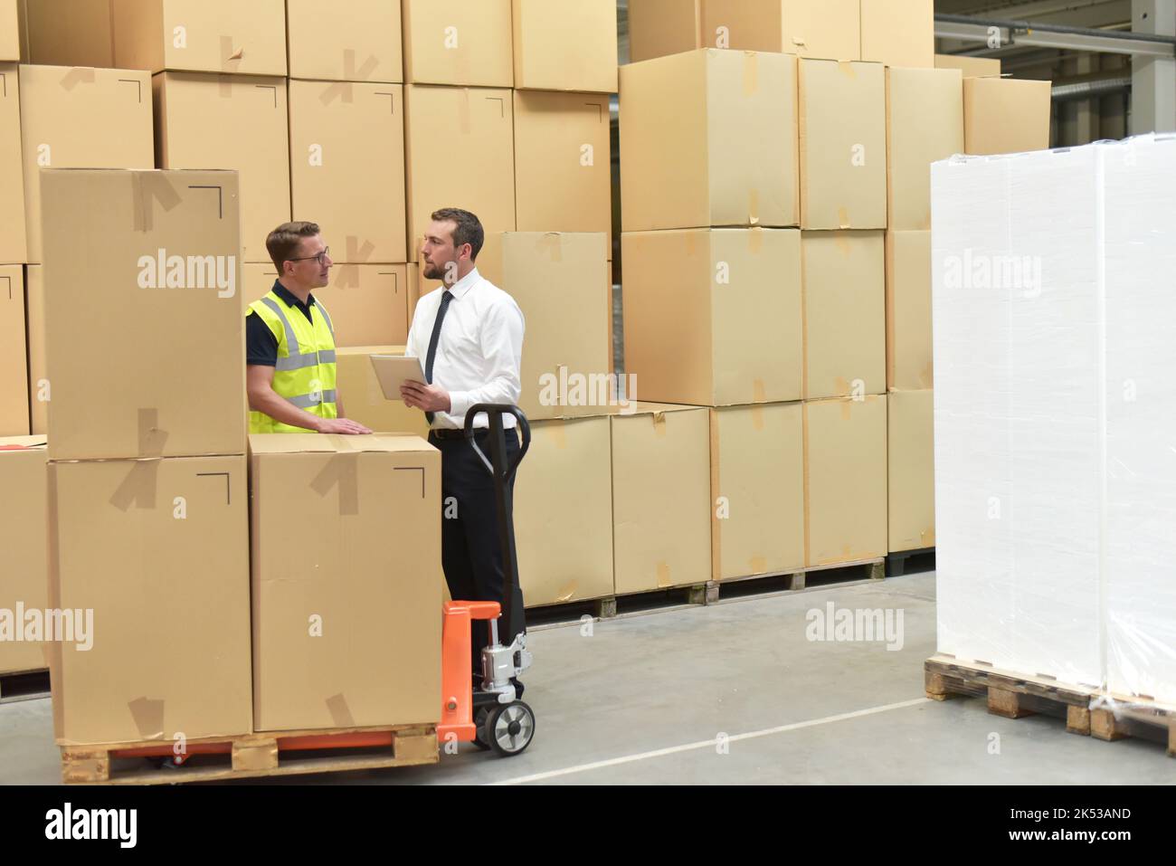 Arbeiter und Geschäftsmann in einem Lager in der Logistik-Branche - Transport und Verarbeitung von Aufträgen im Handel Stockfoto