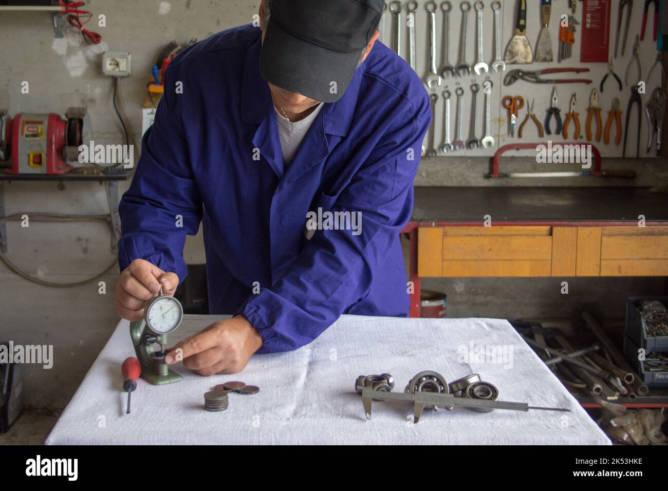 Bild von den Händen eines Mechanikers in seiner Werkstatt, der mit einem Dickenmessgerät mechanische Teile misst. Präzisionsmechanik Stockfoto