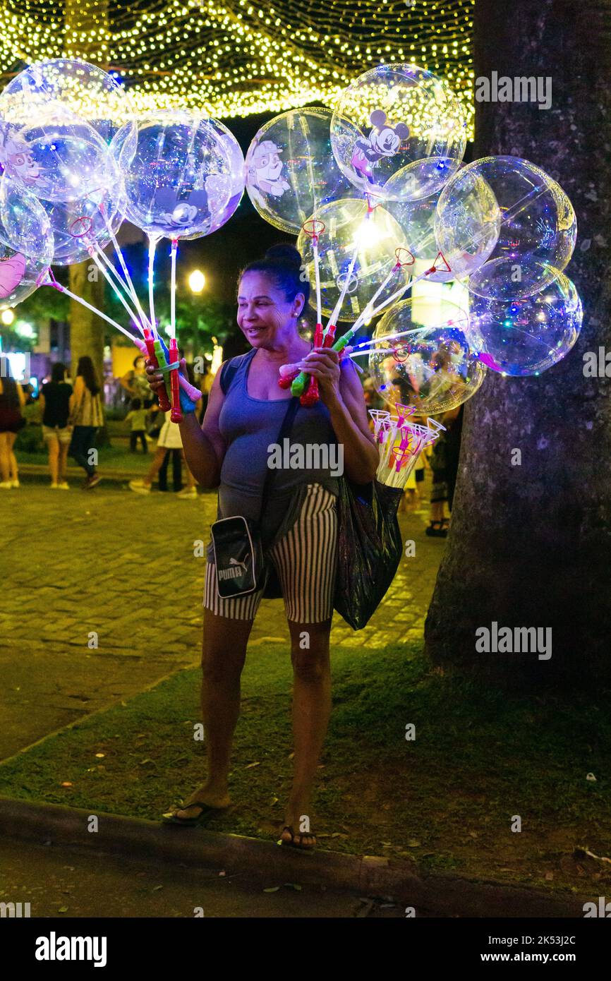Weibliche Verkäuferin, die während der Weihnachtszeit transparente LED-Leuchtballons im Praça da Liberdade in Belo Horizonte, Minas Gerais, Brasilien verkauft. Stockfoto