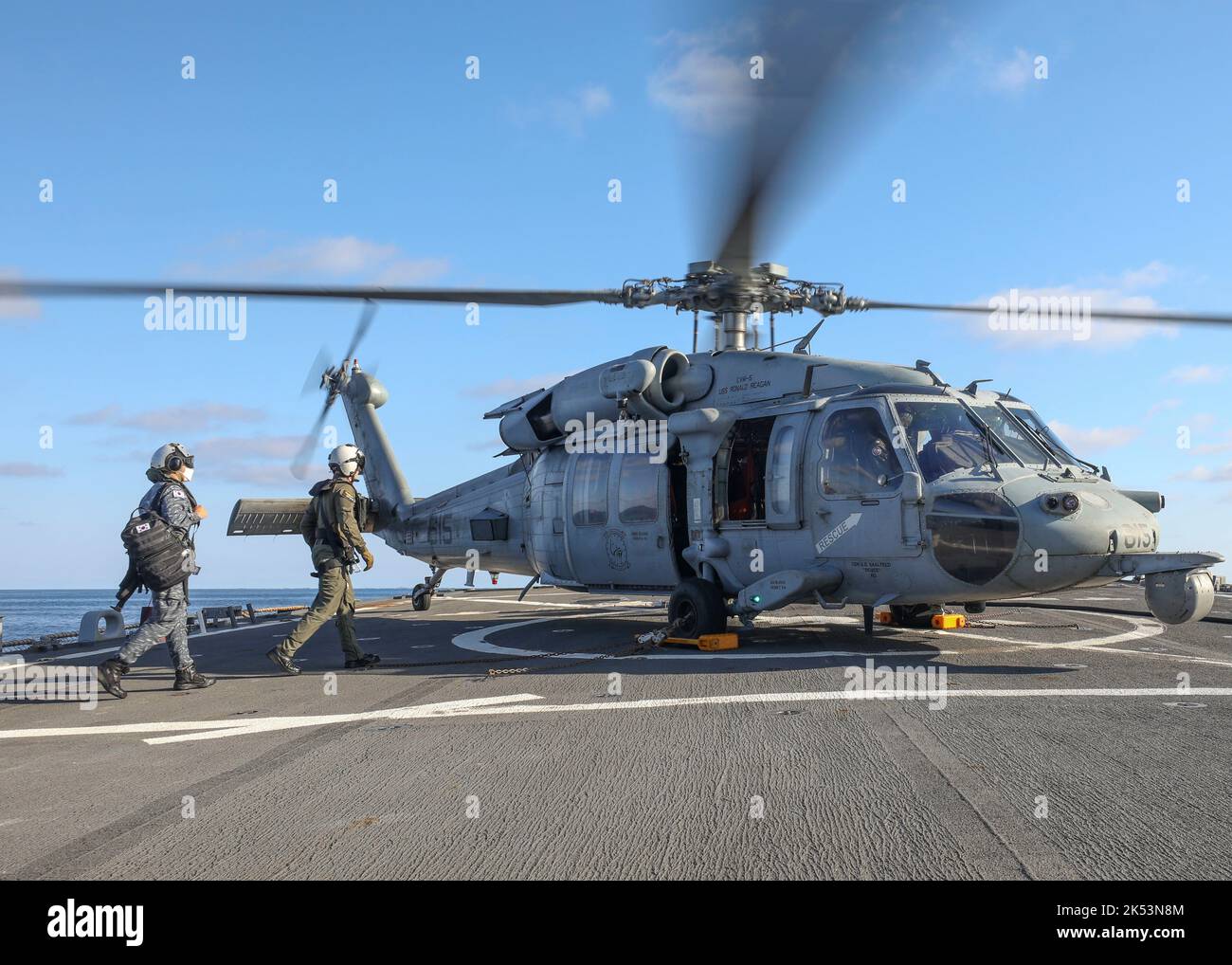 GEWÄSSER ÖSTLICH DER KOREANISCHEN HALBINSEL (SEPT 30, 2022) Marine-Seemann LT. Taehyung Kim, links, bestieg einen MH-60s Sea Hawk Hubschrauber, der den „Golden Falcons“ des HSC-12 an Bord des Arleigh Burke-Klasse Lenkflugkörper-Zerstörers USS Benfold (DDG 65) zugewiesen wurde, Sept. 30. Benfold und die Carrier Strike Group (CSG) 5 führen eine dreilaterale Übung zur Bekämpfung des U-Boot-Kriegs mit der JMSDF und der ROK Navy durch. Die Operationen zwischen der Reagan Strike Group, JS Asahi und ROKS Munmu dem Großen beinhaltete den Betrieb mit einem US-U-Boot, um die Interoperabilität zwischen den Nationen zur Unterstützung einer Freien und Op zu verbessern Stockfoto