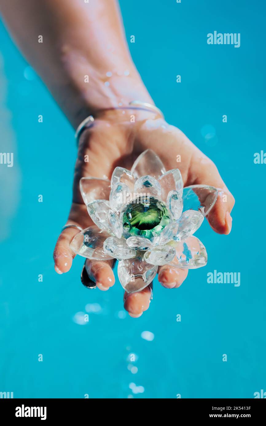 Frau mit zerbrechlicher Lotusblume. Aus dem Kristall tropfen saubere Wassertropfen. Konzept der Religion, Kundalini, Meditation, Chakren, spirituelle innere Stockfoto