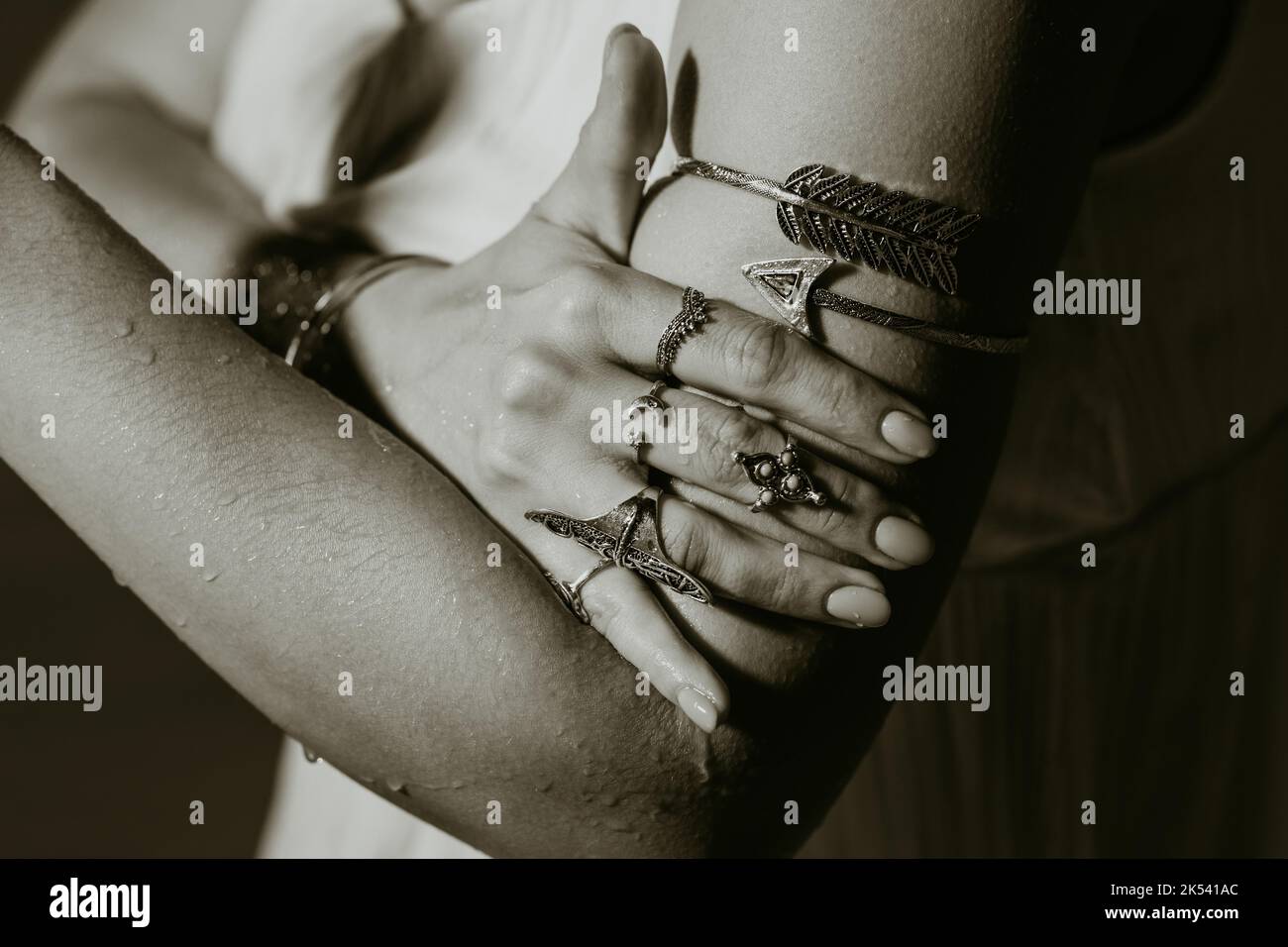 Schöne Zigeunerfrau zeigt Boho Schmuck, Ringe mit türkisfarbenen Steinen an den Händen. Schwarz und Weiß. Mädchen in weißem Kleid zeigt Accessoires in Stockfoto