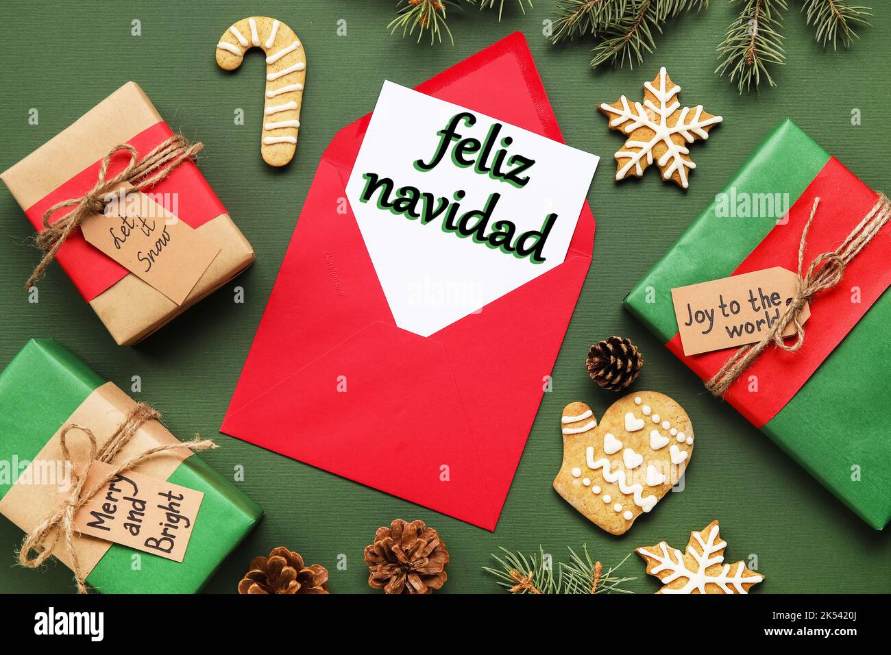 Karte mit Text FELIZ NAVIDAD (Spanisch für Frohe Weihnachten) in Umschlag, Geschenken, Keksen und Dekor auf grünem Hintergrund Stockfoto
