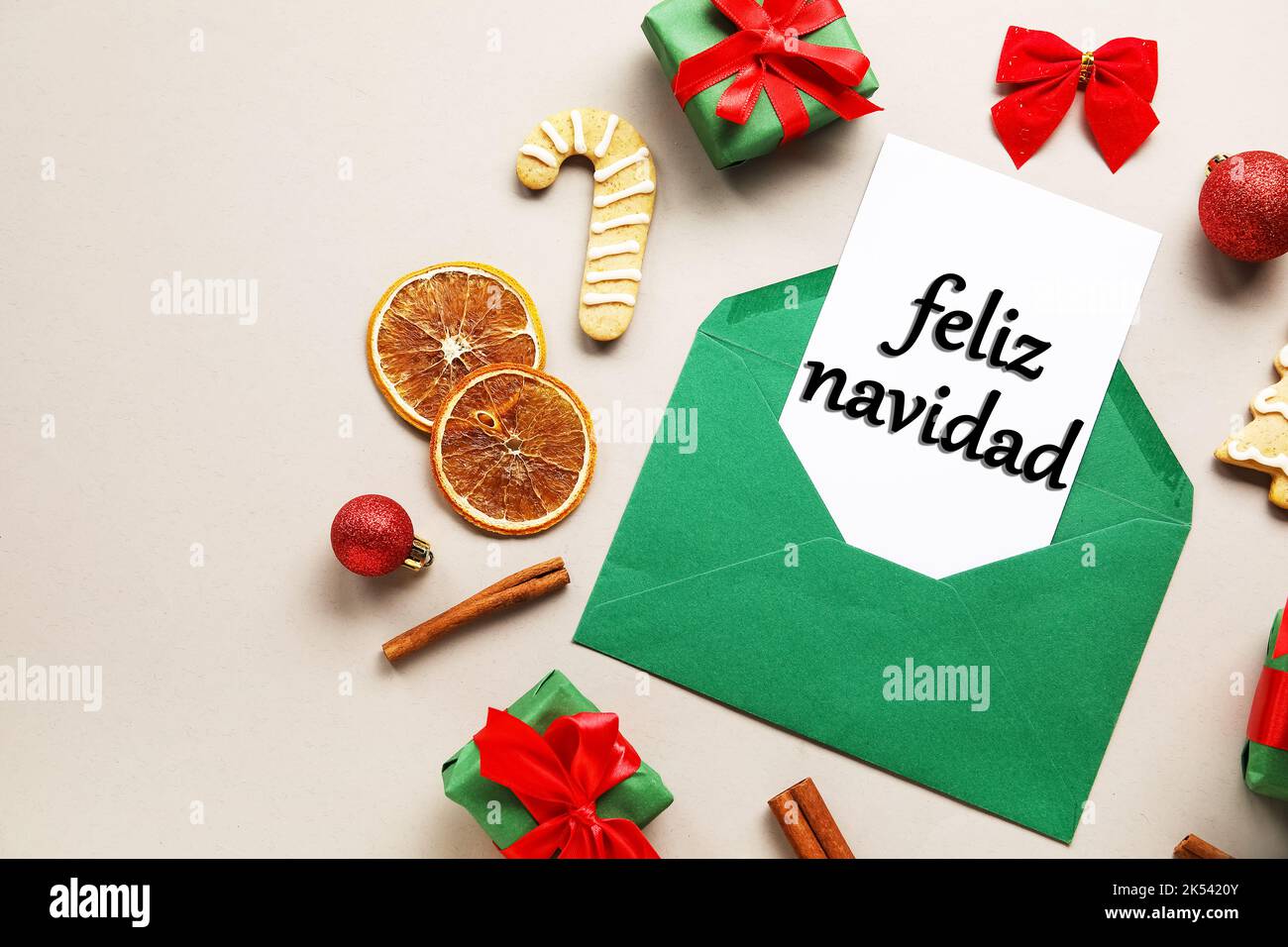Karte mit Text FELIZ NAVIDAD (Spanisch für Frohe Weihnachten) in Umschlag, Geschenken, Essen und Dekor auf hellem Hintergrund Stockfoto
