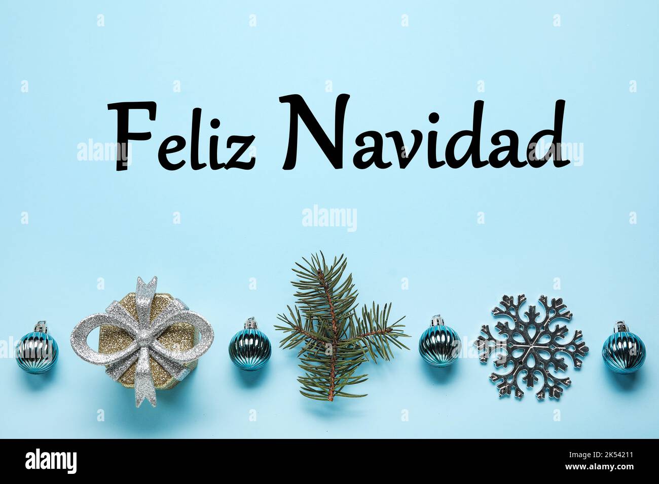 Text FELIZ NAVIDAD (Spanisch für Frohe Weihnachten) und schönes Dekor auf hellblauem Hintergrund Stockfoto
