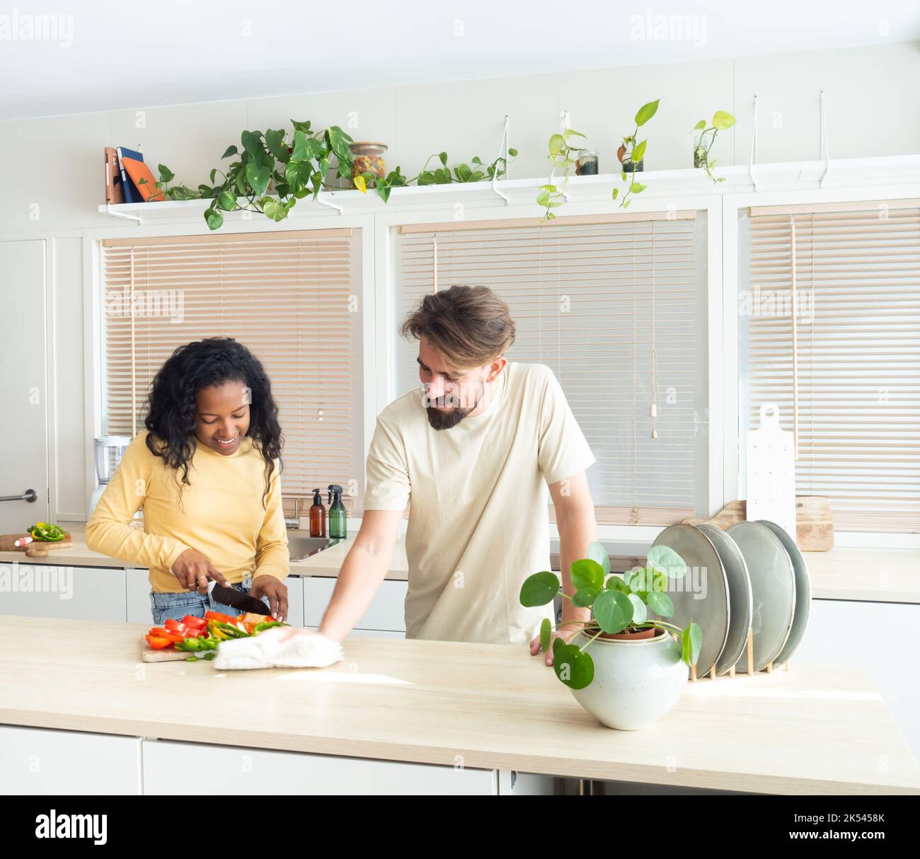 Junges multiethnisches Paar in der Küche beim Kochen und Putzen. Stockfoto