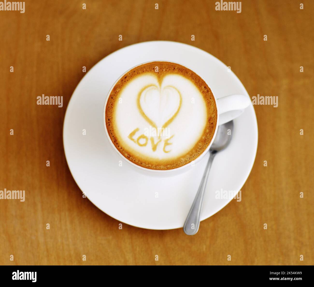 Hergestellt mit liebevollen Händen...Hochwinkelaufnahme einer liebevoll zubereiteten Tasse Cappuccino, die auf einem Kaffeetisch sitzt. Stockfoto