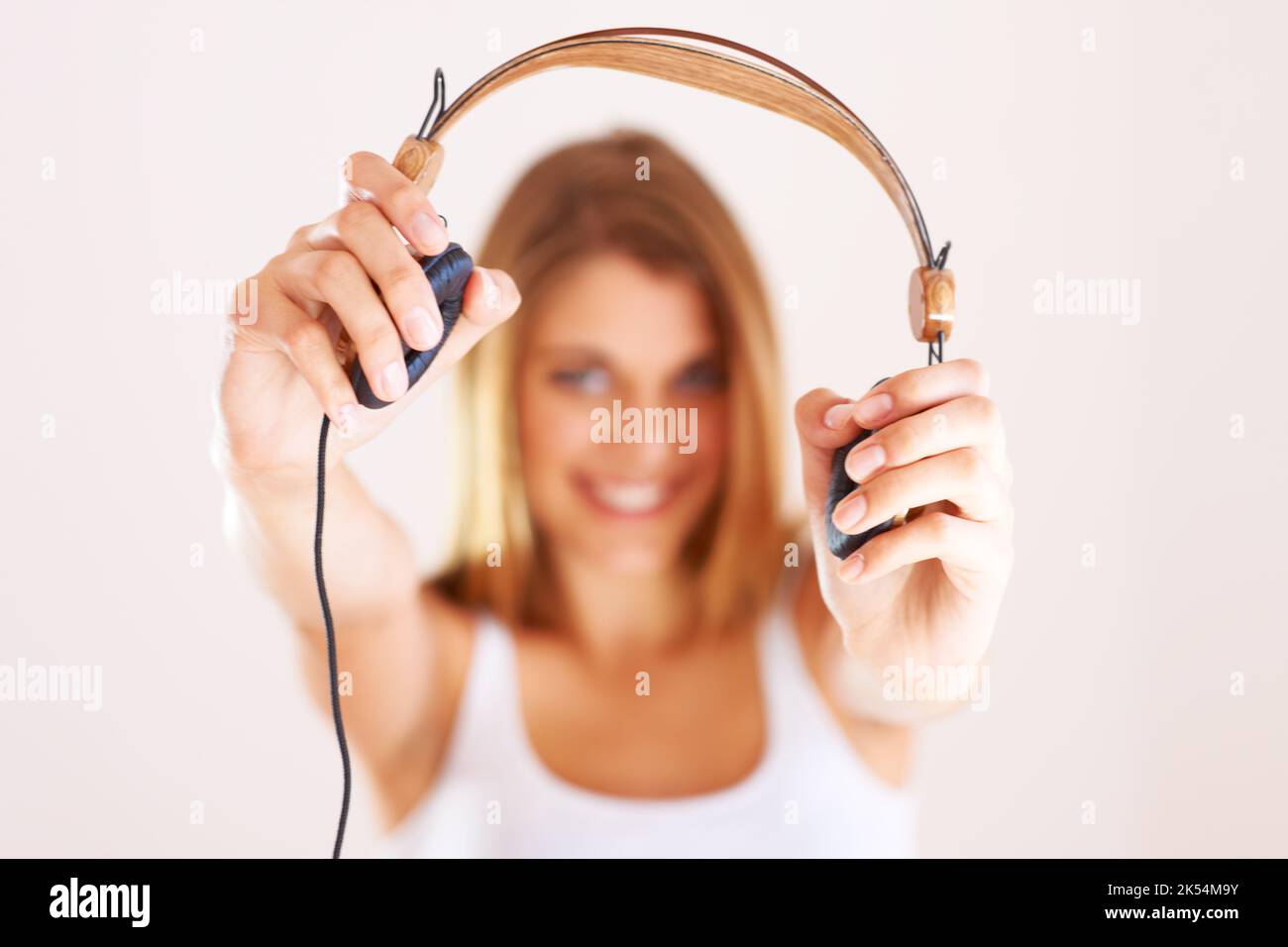 Du musst dieses Lied hören. Eine junge Frau hält Ihnen ihre Kopfhörer vor. Stockfoto