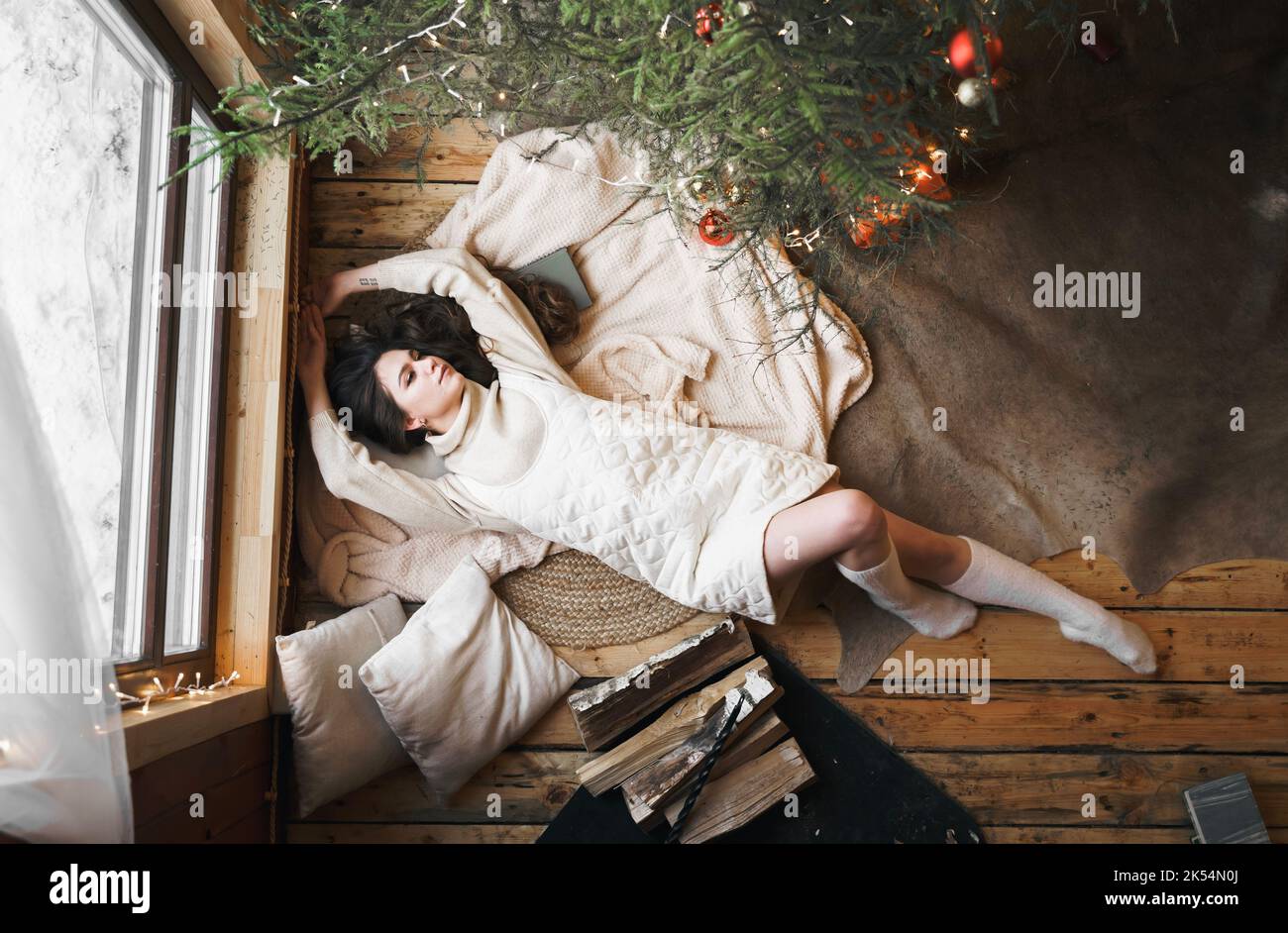 Junge stilvolle Mädchen liegt auf der Haut auf dem Boden in gemütlichen Holz Landhaus, Chalet im Winterwald. Wir feiern Silvester. Geschenke, Familienurlaub. Romanti Stockfoto