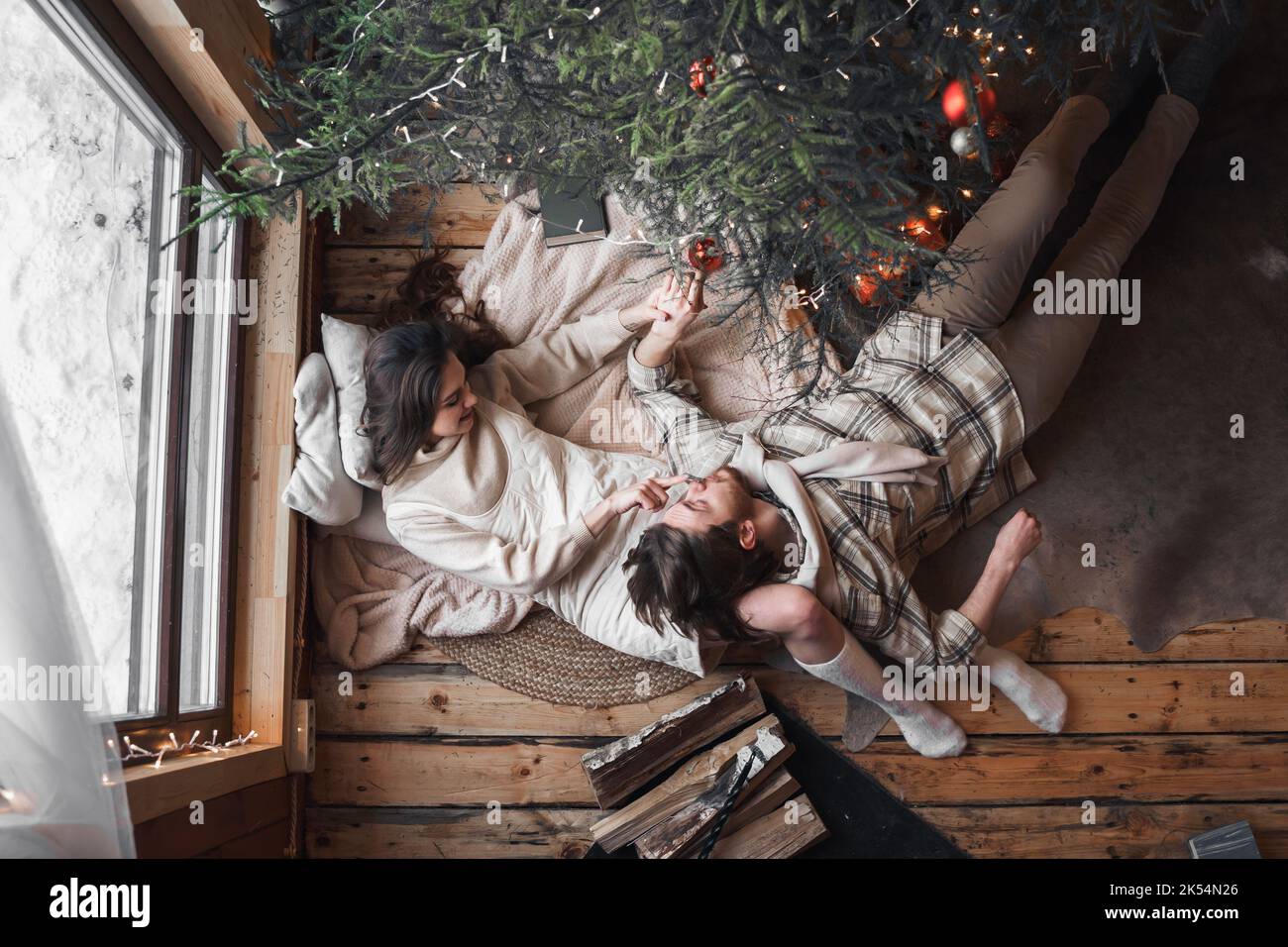 Junge stilvolle Liebe Paar Mädchen, Kerl liegen auf der Haut auf dem Boden in gemütlichen Holz Landhaus, Chalet im Winterwald. Wir feiern Silvester. Geschenke, Familie Stockfoto