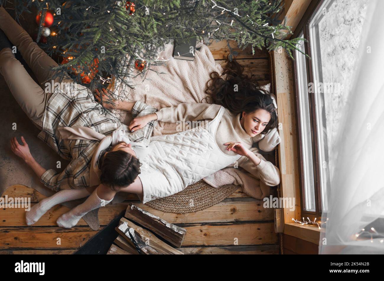 Junge stilvolle Liebe Paar Mädchen, Kerl liegen auf der Haut auf dem Boden in gemütlichen Holz Landhaus, Chalet im Winterwald. Wir feiern Silvester. Geschenke, Familie Stockfoto