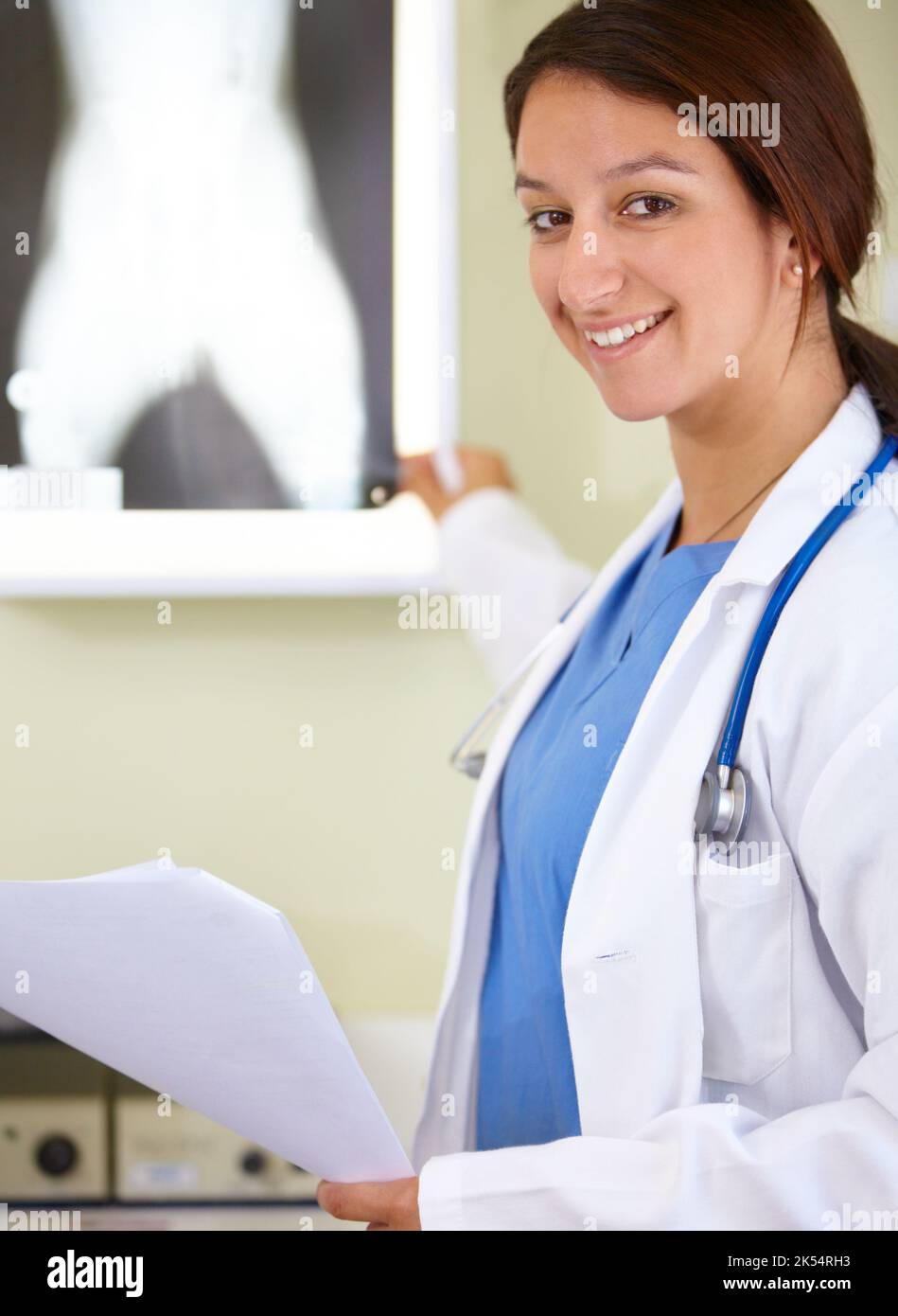 Aufzeigen der Lösung des Problems -X-Ray. Porträt einer jungen Frau in der Ärzteschaft, die auf eine Röntgenaufnahme zeigt. Stockfoto