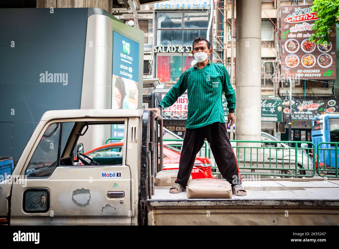 Thailändische Bauarbeiter entladen Zement oder Kies von der Rückseite eines Lastwagens auf der Silom Rd. Bangkok Thailand. Stockfoto