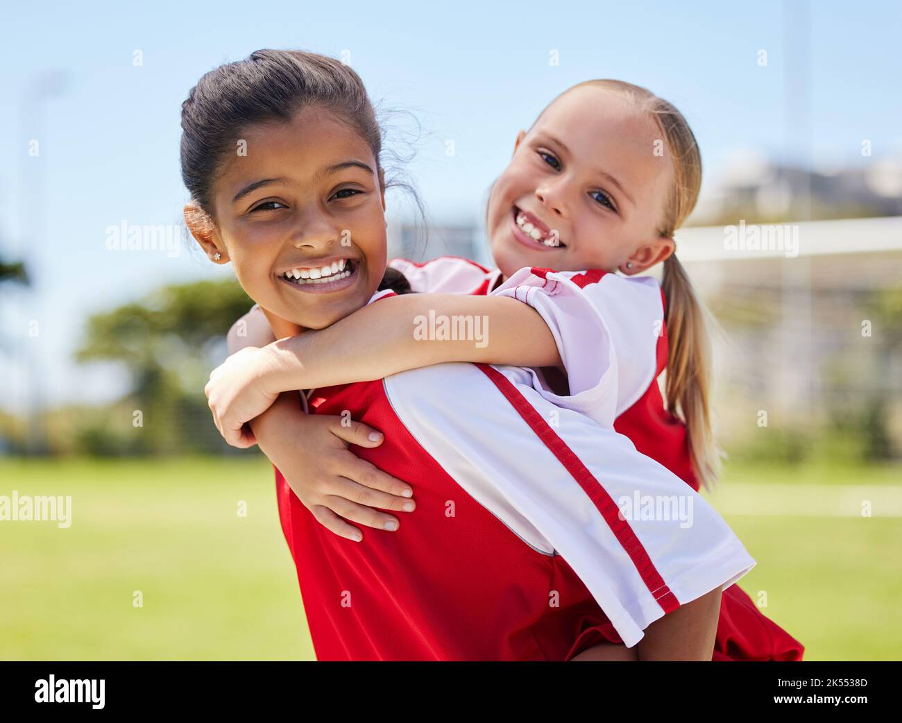 Team-, Sport- und Fußballspielerin Mädchen Kinder mit einem glücklichen Lächeln Spaß auf einem Outdoor-Fußballplatz. Glücksporträt von Kindern vor einem Sportspiel Stockfoto