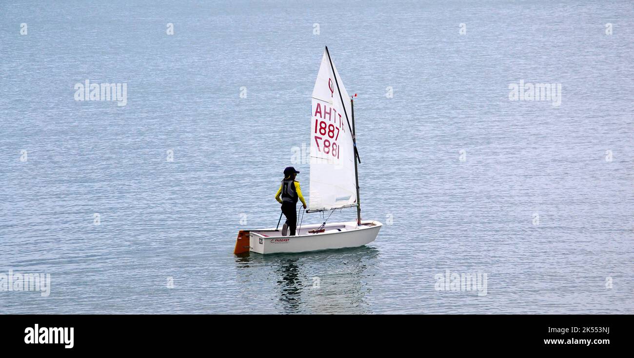 Ein junger Mensch, allein, segelt ein kleines Schlauchboot auf See in Jomtien, Pattaya, Thailand, Südostasien. Stockfoto