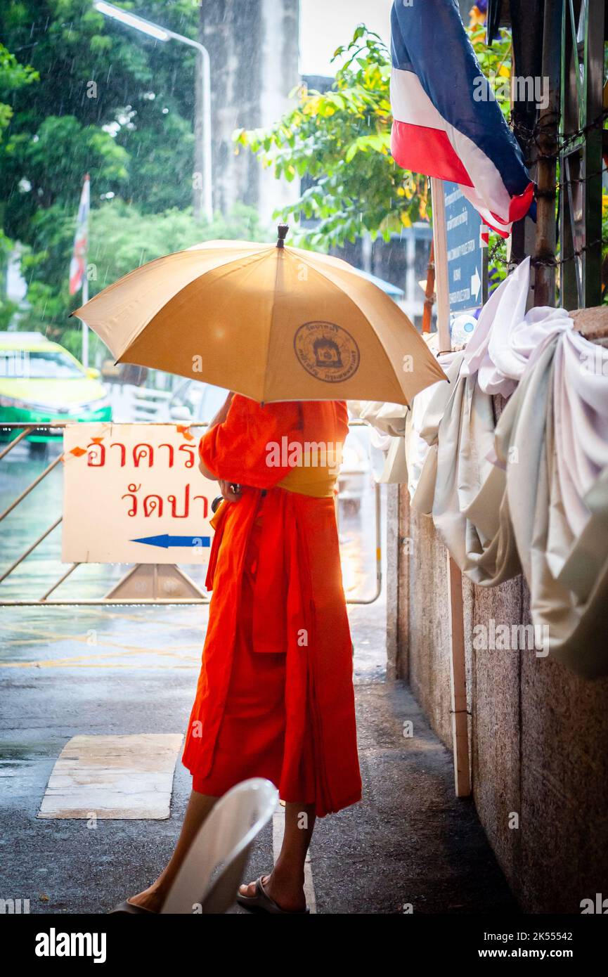 Ein thailändischer Mönch unterm Regenschirm bei einer Regendusche im ...