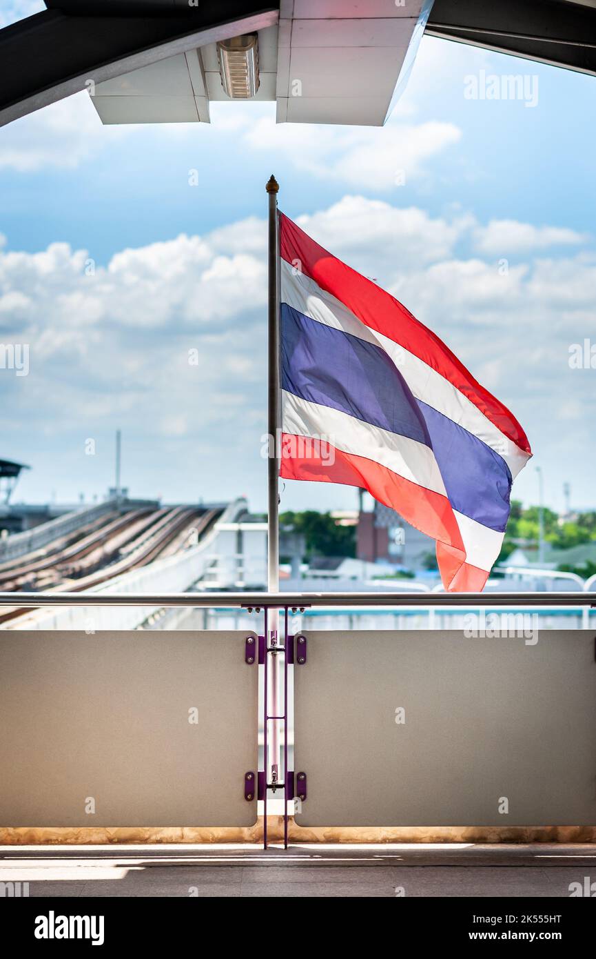 Die thailändische Nationalflagge fliegt im Wind auf dem Bahnsteig einer der BTS-Skytrain-Stationen in Bangkok. Stockfoto