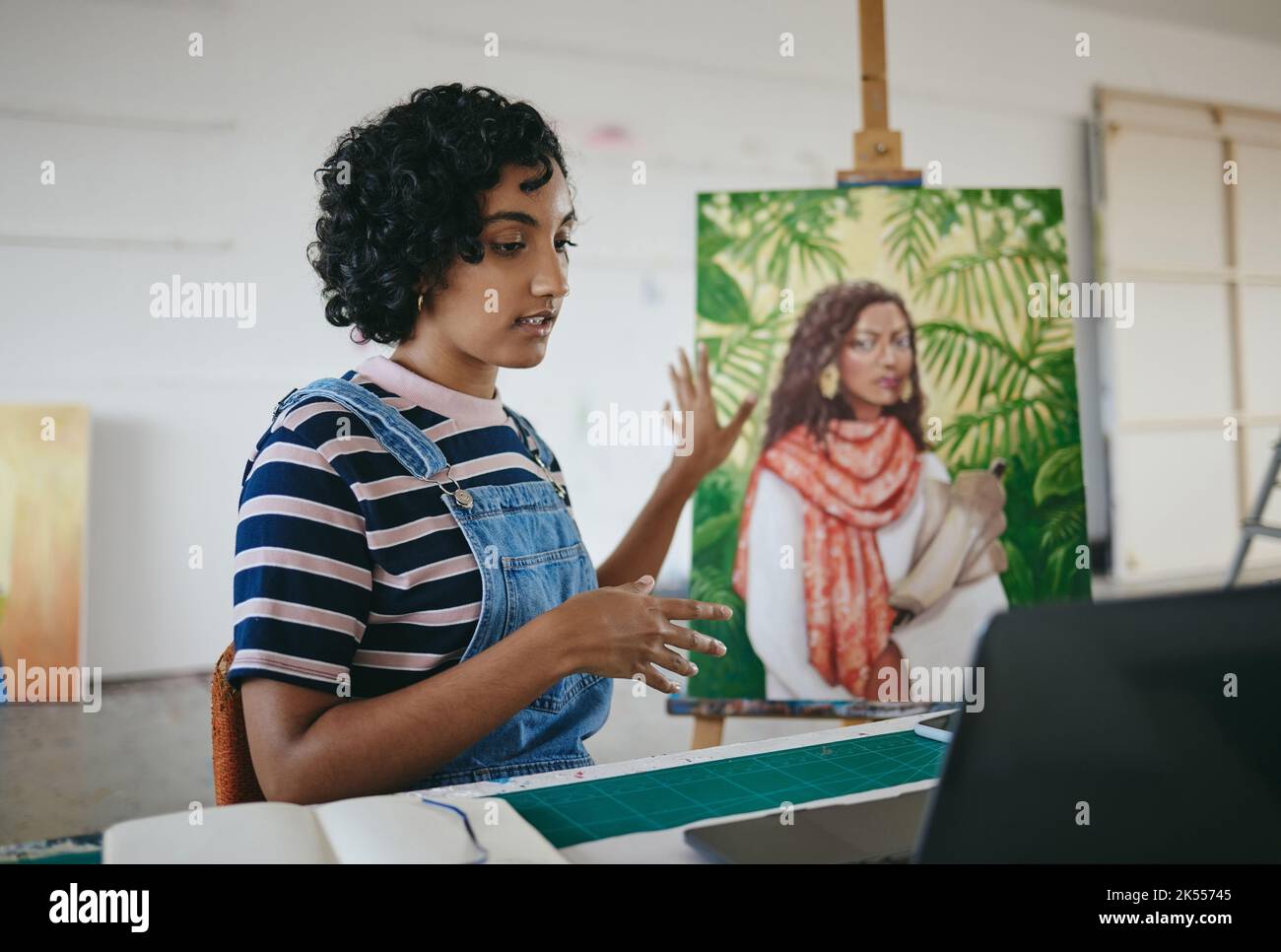 Maler, Künstler und Laptop-Video-Anruf in kreativen Studio für E-Commerce-Verkauf von Leinwandmalerei online. Junge inderin, voip-Kommunikation Chat und Stockfoto