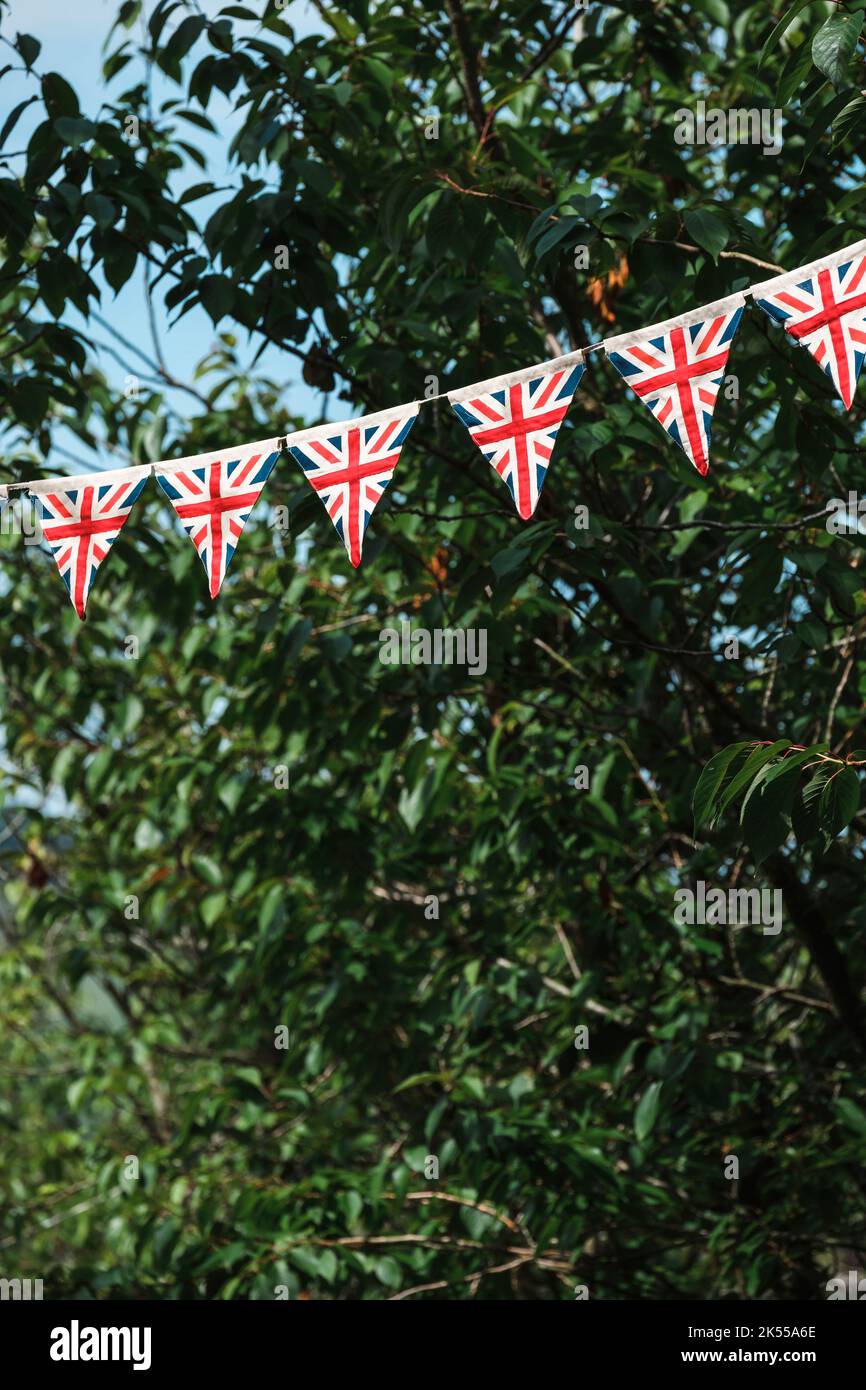 Dreieckige Flaggen des Union Jack hängen an einer von Bäumen gesäumten Allee für die Feierlichkeiten zum Platin-Jubiläum der britischen Königin. Stockfoto
