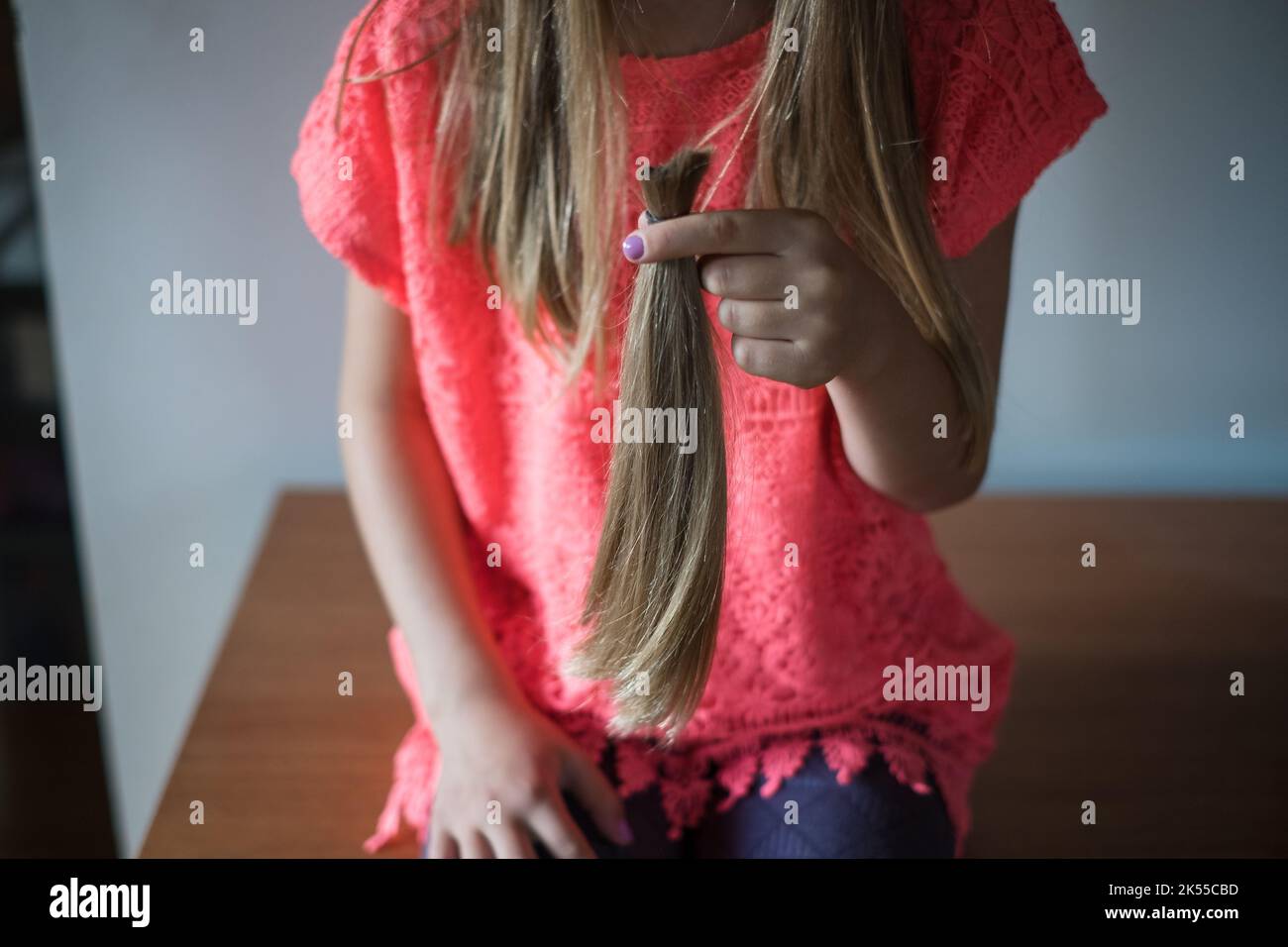 Mädchen hält ihre lange abgeschnitten natürlichen blonden Pferdeschwanz Haar gebunden zusammen. Stockfoto