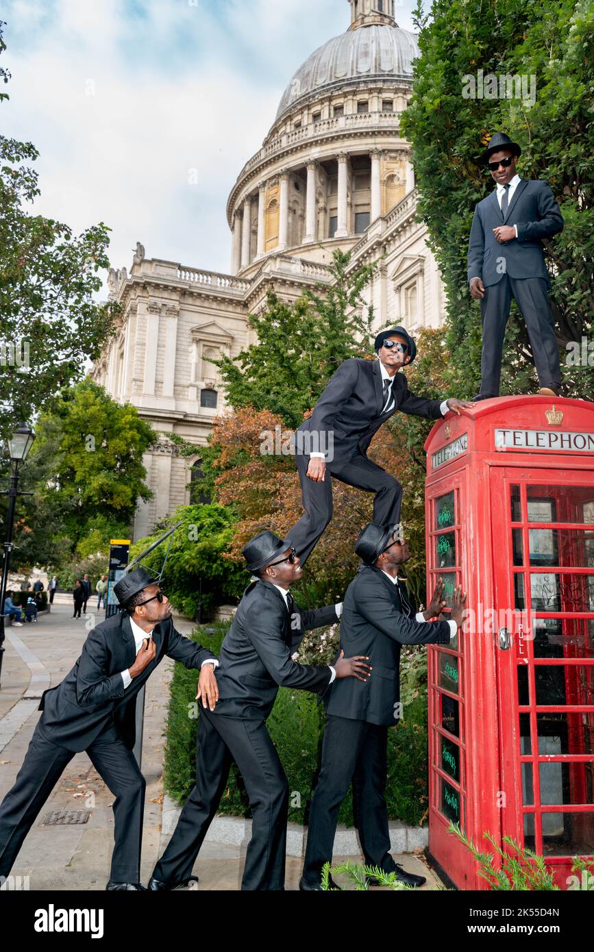 Bilal Musa Huka, Rashid Amini Kulembwa, Seif Mohamed Mlevi, Peter Mnyamosi Obunde und Mohamed Salim Mwakidudu AKA die Black Blues Brothers zeigen ihre akrobatischen Fähigkeiten auf und in einer roten londoner Telefonbox vor dem Hinterabwurf der St. Paul's Cathedral. Die Black Blues Brothers sind eine Gruppe von Akrobaten, die für Papst Franziskus im Vatikan, in der britischen Königsfamilie und bei der Royal Variety Show aufgetreten sind. Die Black Blues Brothers sind mit ihrer Show, die eine akrobatische Hommage an den legendären Kultfilm darstellt, auf UK-Tour. Die Black Blues-Brüder verwendeten eine ikonische London Red Phone Box für ein p Stockfoto