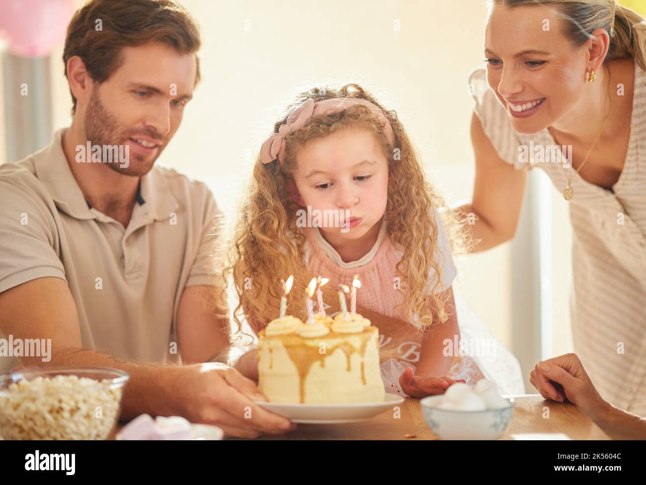 Geburtstag, Kerzen und Familienfest mit Kuchen, Eltern und Mädchen für ein glückliches Familienfest. Glück, Liebe und Lächeln einer Mutter, eines Vaters und eines jungen Kindes Stockfoto