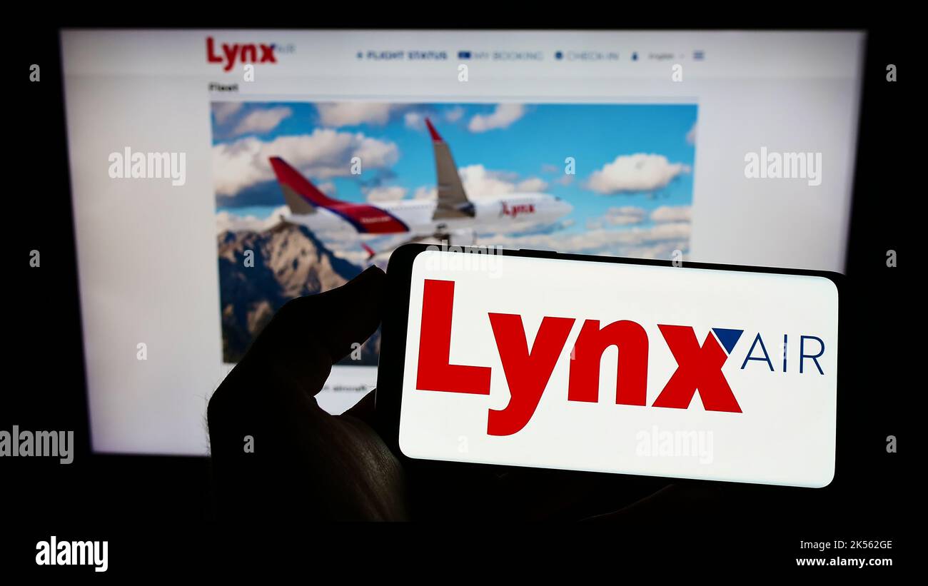 Person mit Mobiltelefon und Logo der kanadischen Fluggesellschaft Lynx Air (1263343 Alberta Ltd.) auf dem Bildschirm vor der Webseite. Konzentrieren Sie sich auf die Telefonanzeige. Stockfoto