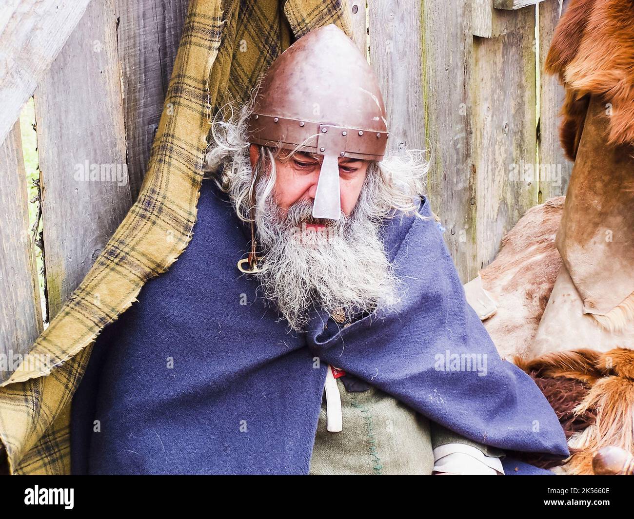 Ein bärtiger Mann trägt mittelalterliche Kleidung und einen Eisenhelm mit Nasenschutz. Stockfoto
