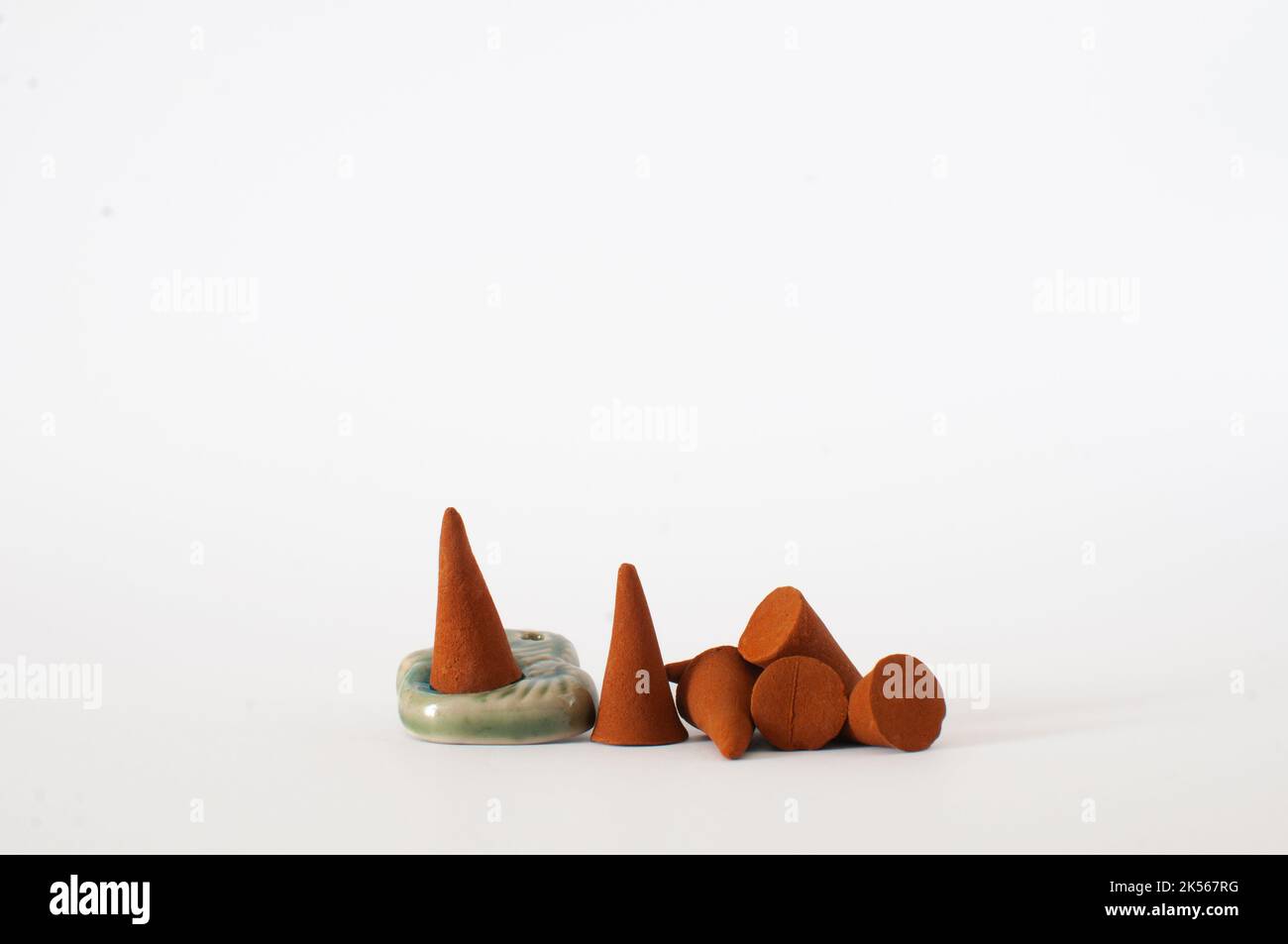 Gruppe von natürlichen Aroma braunen Räucherkegel mit Keramikhalter isoliert auf weißem Hintergrund mit selektivem Fokus. Stockfoto