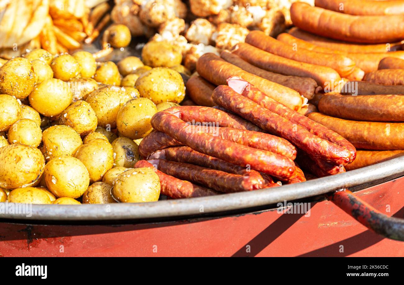 Saftig appetitlich gegrillte Würstchen und gebackene Kartoffeln in einer Pfanne Stockfoto