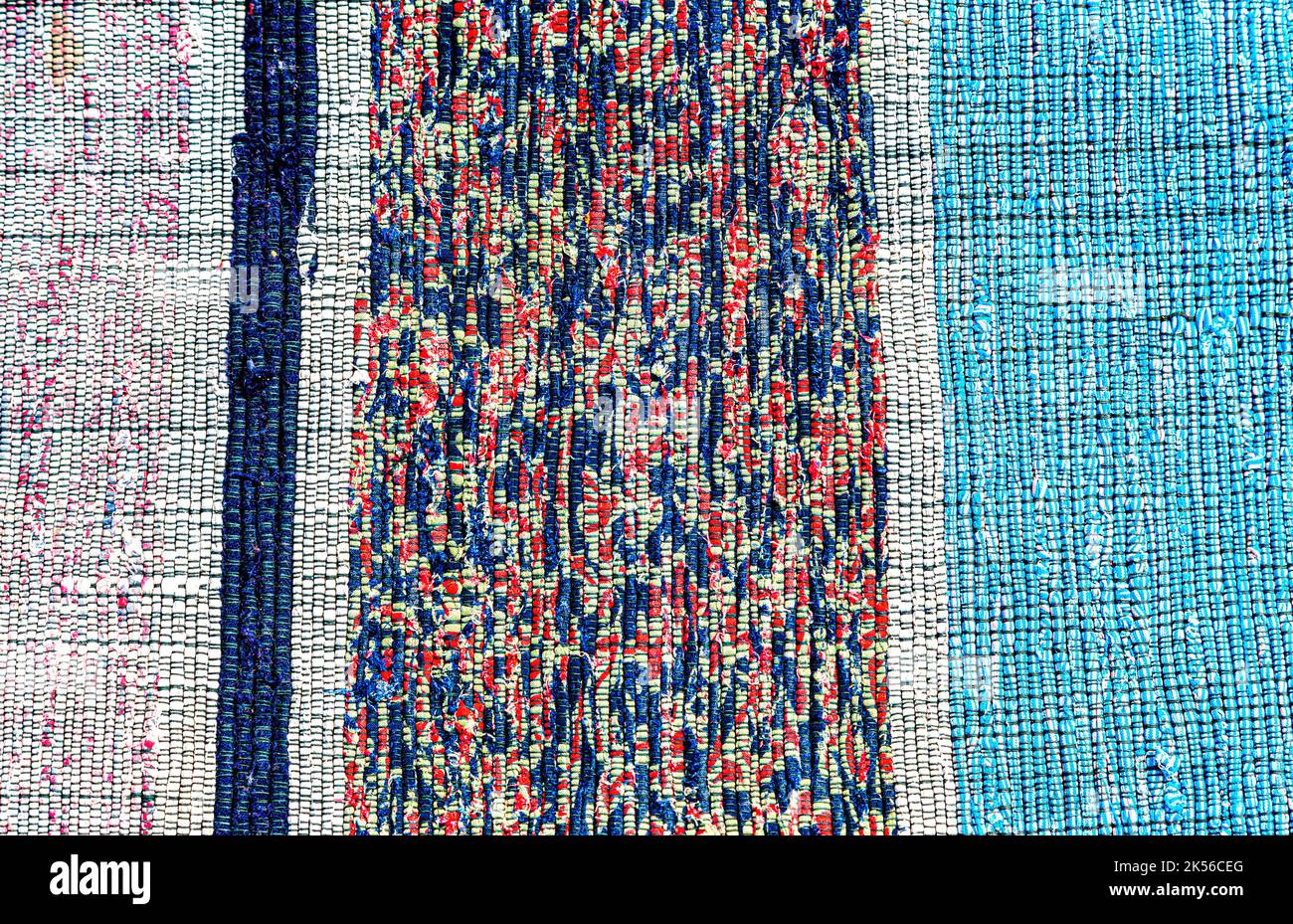 Vintage homespun Fußmatte aus Streifen von Stoff als Hintergrund gemacht. Textur einer hausgemachten Wolldecke aus verschiedenen Stoffen Stockfoto