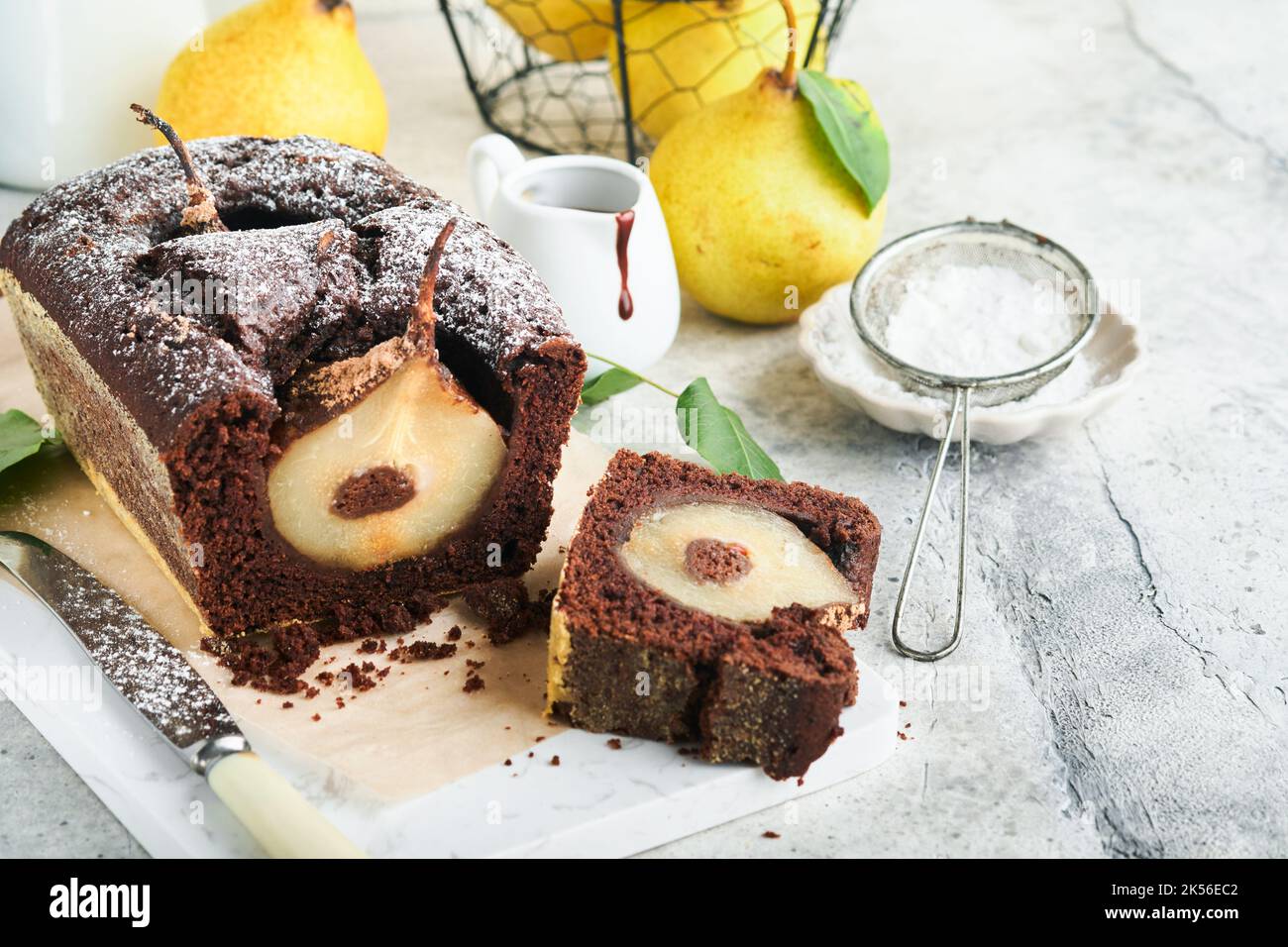 Schokoladenkuchen mit Birnen im Inneren gebacken. Schokoladen-Birne-Kuchen oder dunkler Schoko-Bundtkuchen mit Birne auf hellgrauem Tisch zu Hause. Hausmannskost und bakin Stockfoto