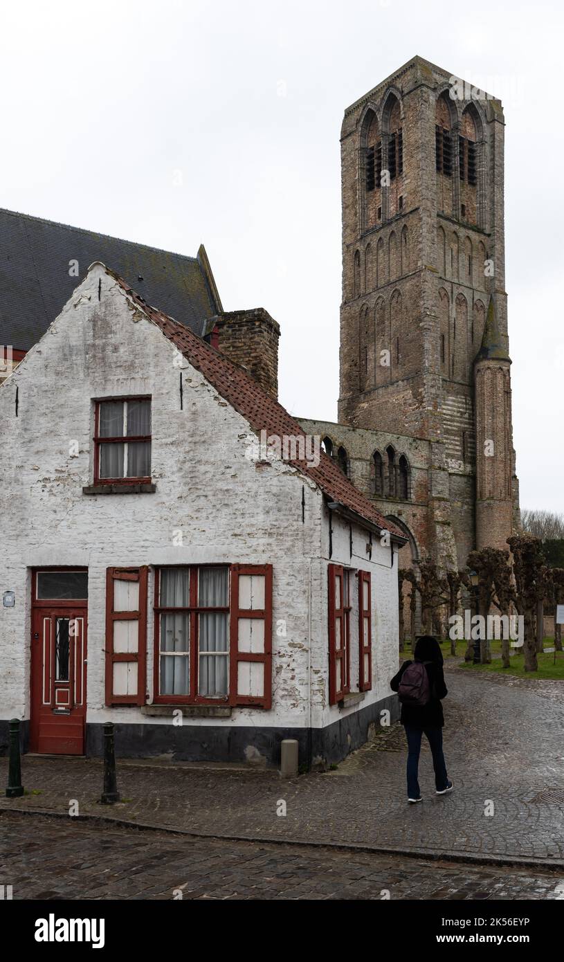 Damme, Flämische Region - Belgien - 04 04 2021 Turm einer mittelalterlichen rechteckigen Kirche und eines alten Bauernhauses Stockfoto