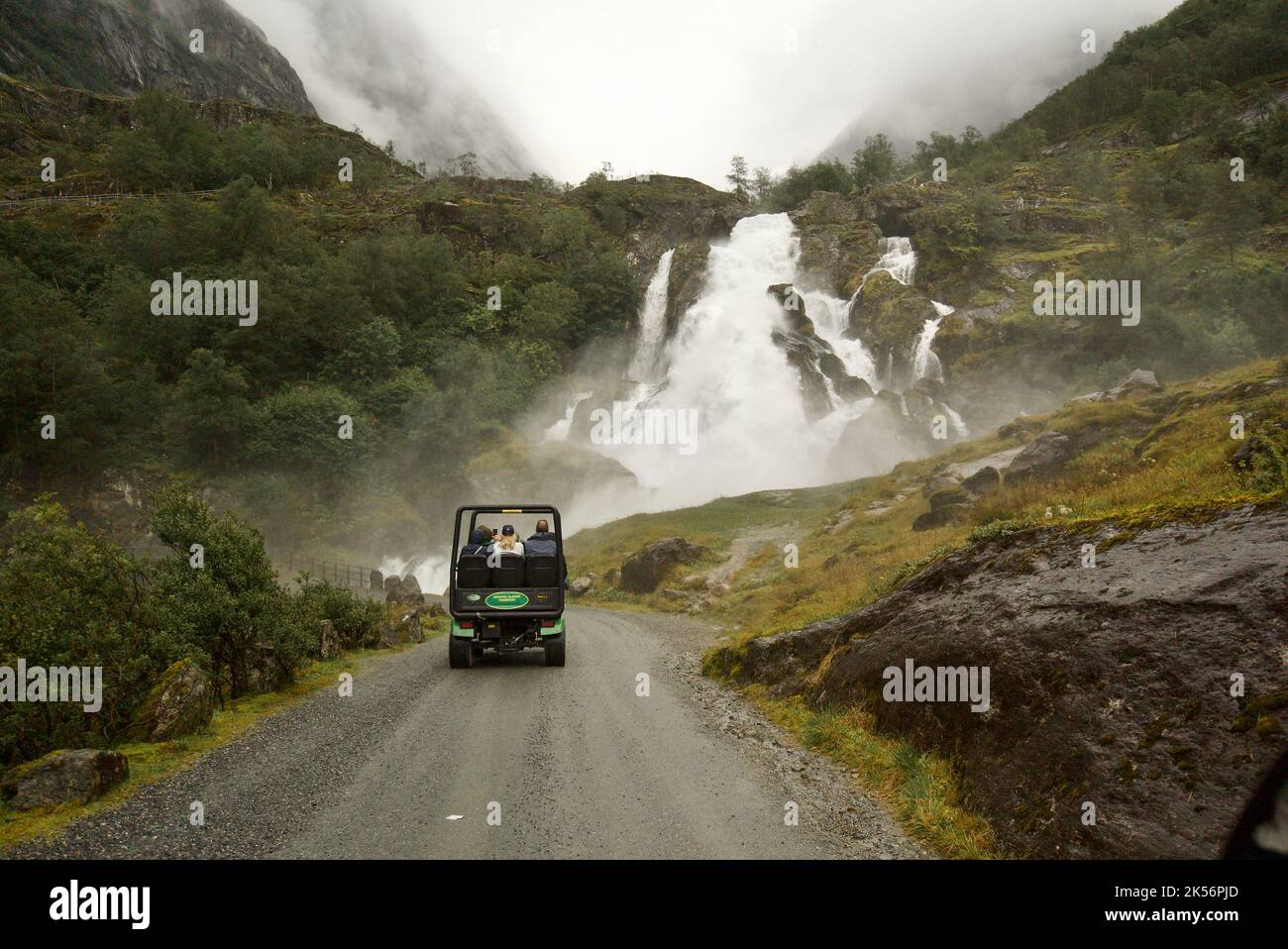 Ein Trollauto, das einen Berg hinauf fährt, vorbei an Wasserfällen, zum Briksdal Glacier, Briksdalsbreen. Ein touristischer Gletscher-Shuttle - Briksdalsbre. Stockfoto