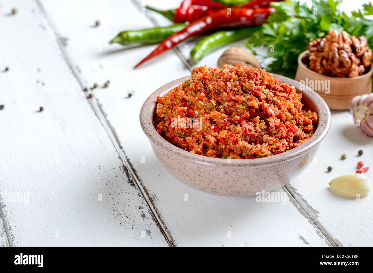 Adjika in einer Schüssel auf einem weißen Holztisch. Würzige Sauce für Fleischgerichte. Speicherplatz Kopieren. Stockfoto