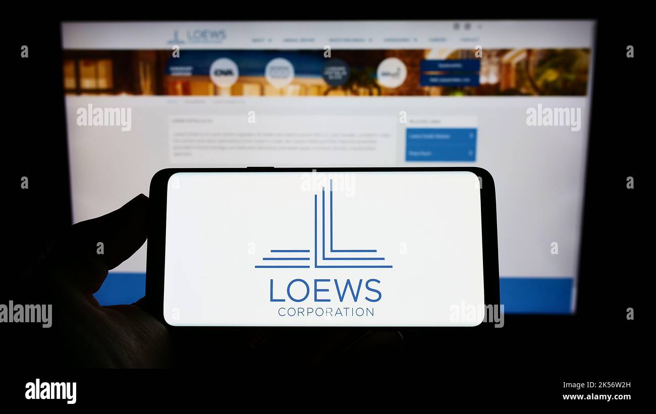 Person, die das Smartphone mit dem Logo des US-amerikanischen Konglomerats Loews Corporation auf dem Bildschirm vor der Website hält. Konzentrieren Sie sich auf die Telefonanzeige. Stockfoto