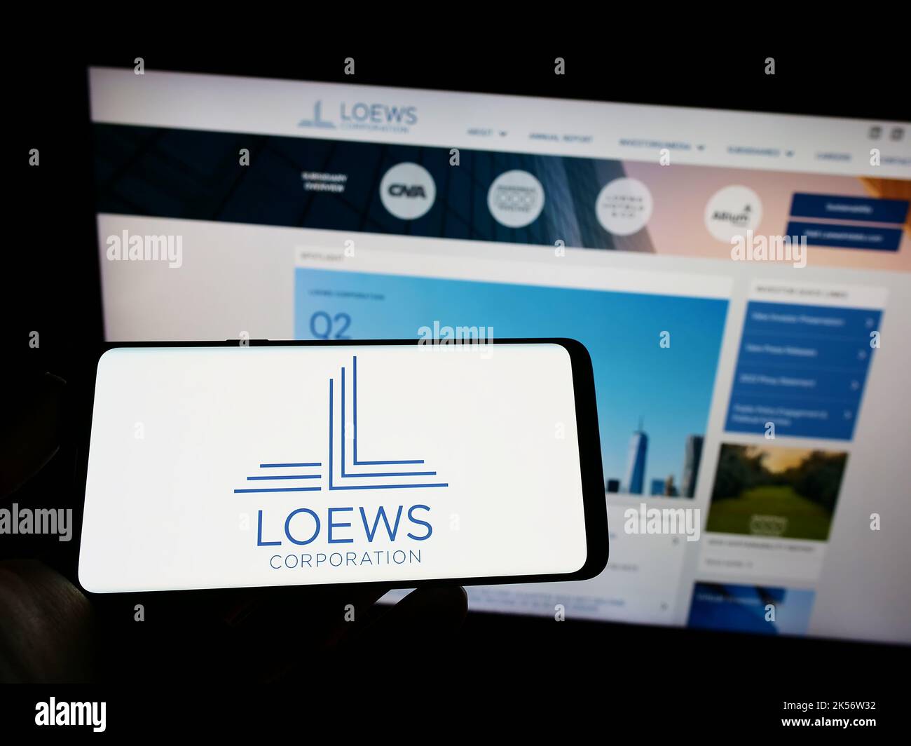 Person mit Mobiltelefon und Logo des US-amerikanischen Konglomerats Loews Corporation auf dem Bildschirm vor der Business-Webseite. Konzentrieren Sie sich auf die Telefonanzeige. Stockfoto