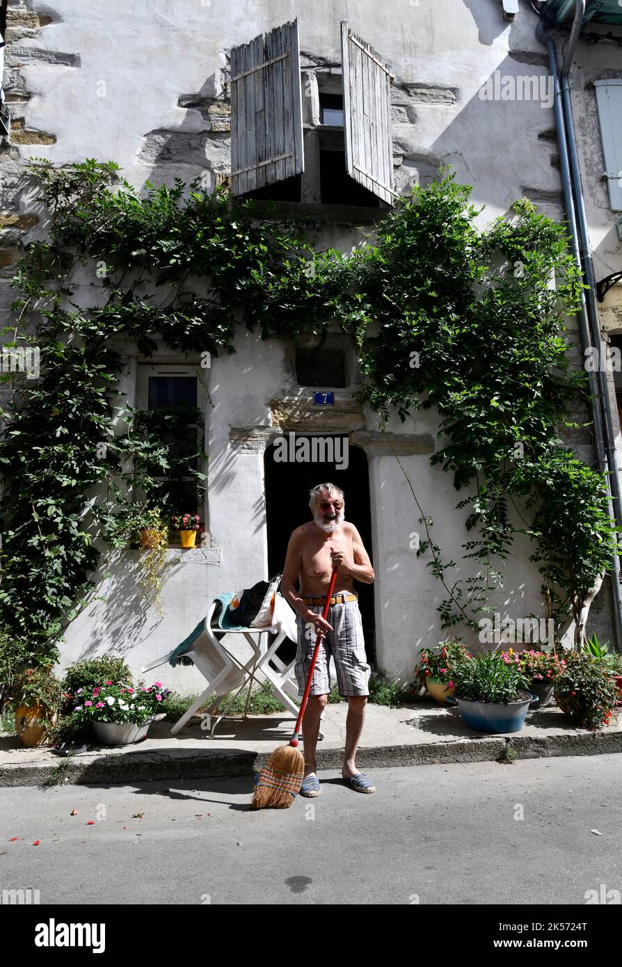 Französischer Mann, der die Straße vor seinem Haus im historischen Dorf Salies-de-Bearn, Frankreich, fegen muss Stockfoto