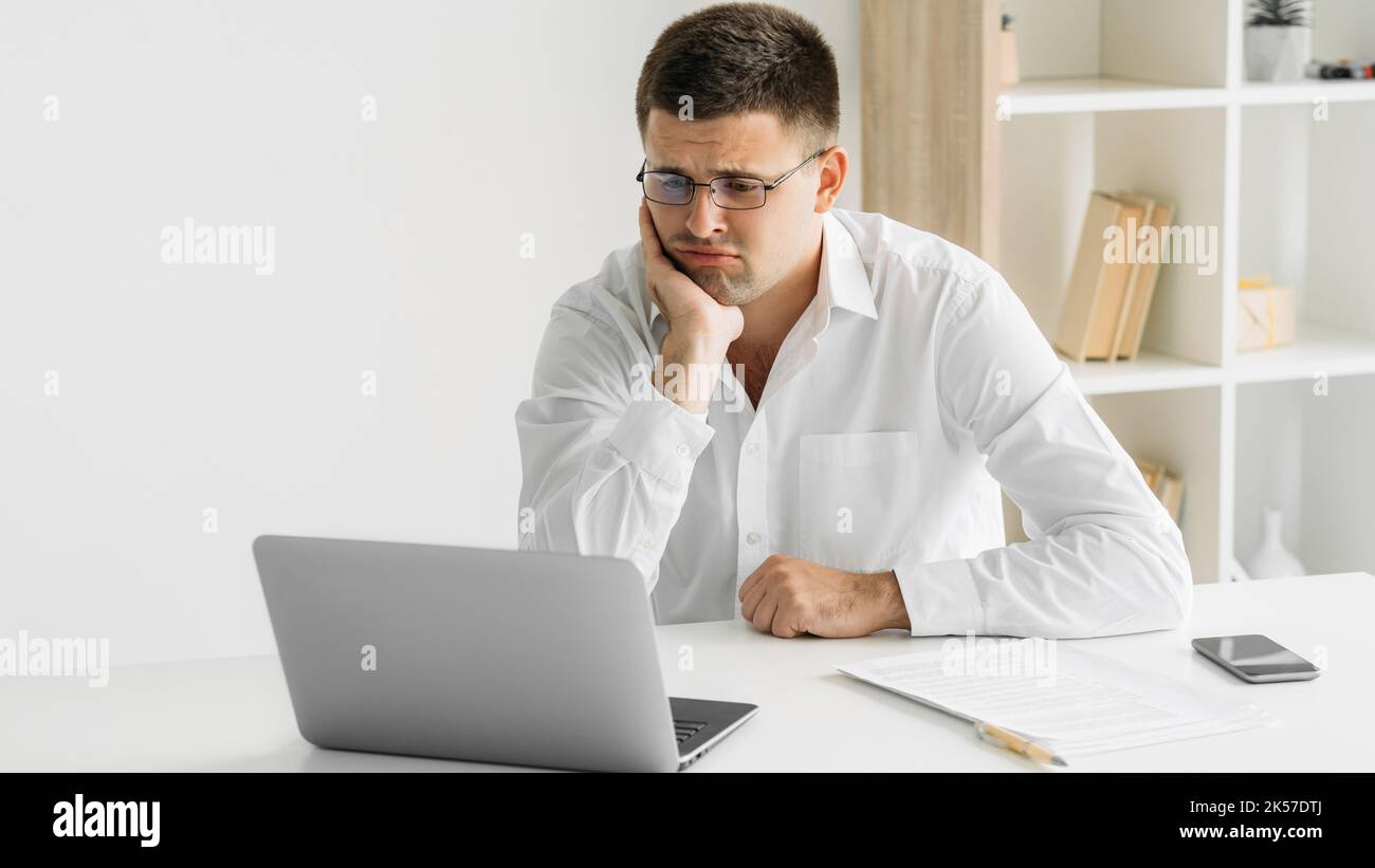 Gelangweilter Mann desinteressiert arbeiten alberne Aufgaben skeptisch Stockfoto